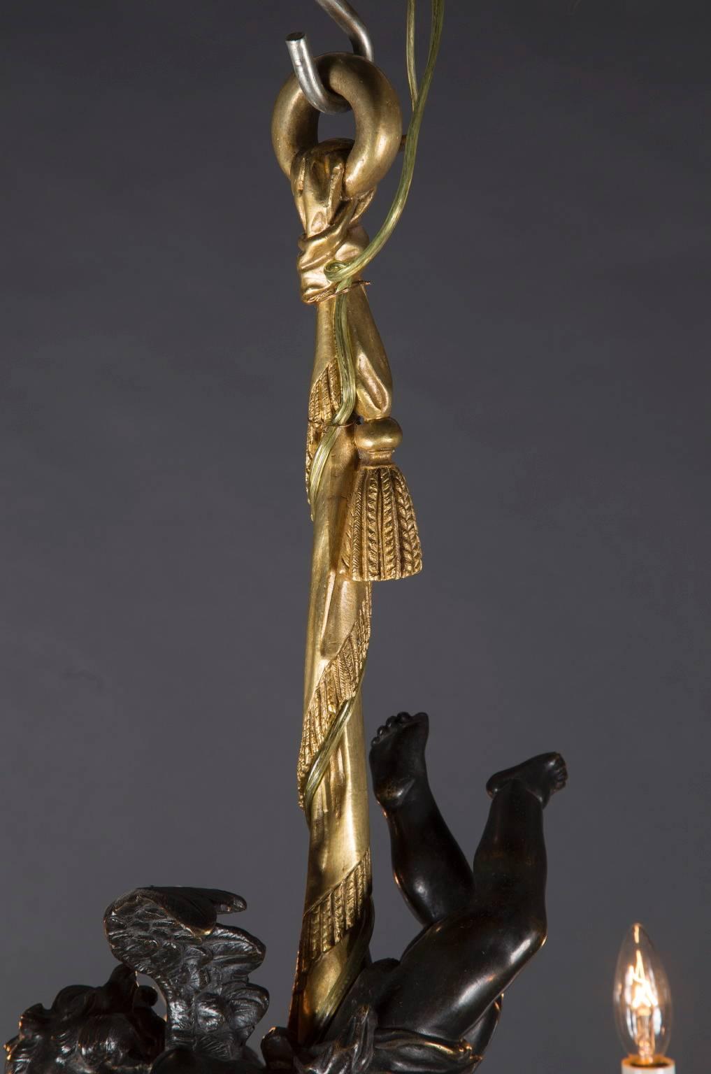Fabriqué en France au XIXe siècle, ce lustre est en bronze massif teinté d'or avec un chérubin ailé en bronze patiné serrant la tige centrale. Les bras du lustre sont un bouquet de fleurs, tous liés à la base, chaque bobèche étant une fleur. La tige