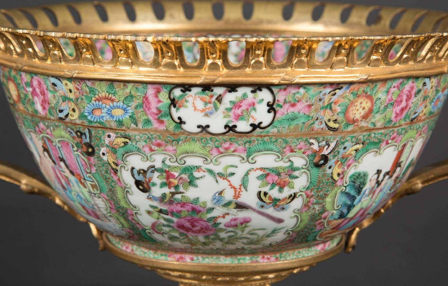 The porcelain bowl of this centerpiece was made in China and exported to France, where French craftsmen added the handles, rim, and base to it, all constructed of solid bronze. The handles are made in geometric patterns, with a wreath hanging from