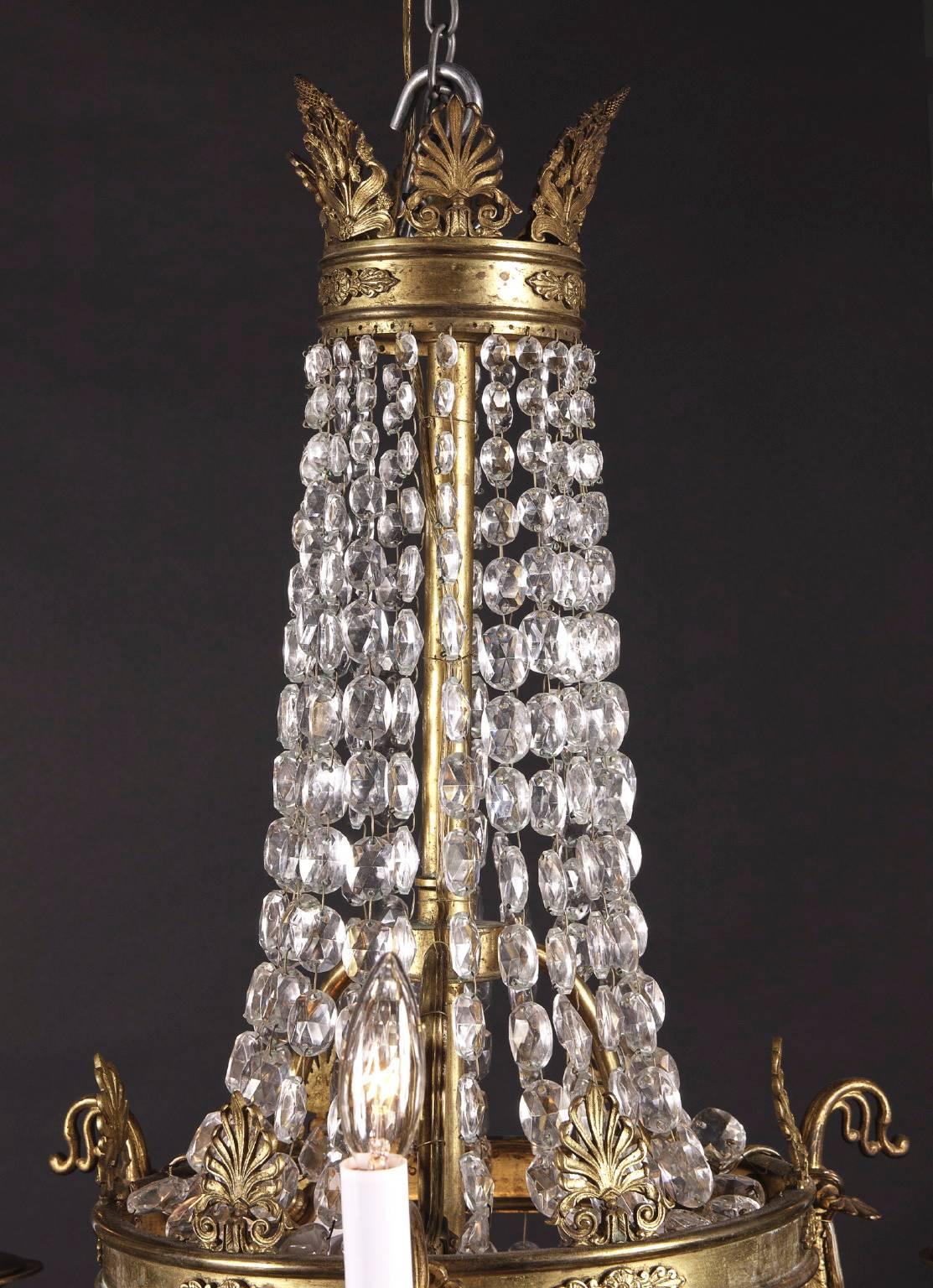 This small chandelier is from France and is made of beautiful bronze and crystal elements. A bronze ring rests at the center of the chandelier, with palm fronds rising out the top of it. Crystals cascade down from the top of the chandelier to this