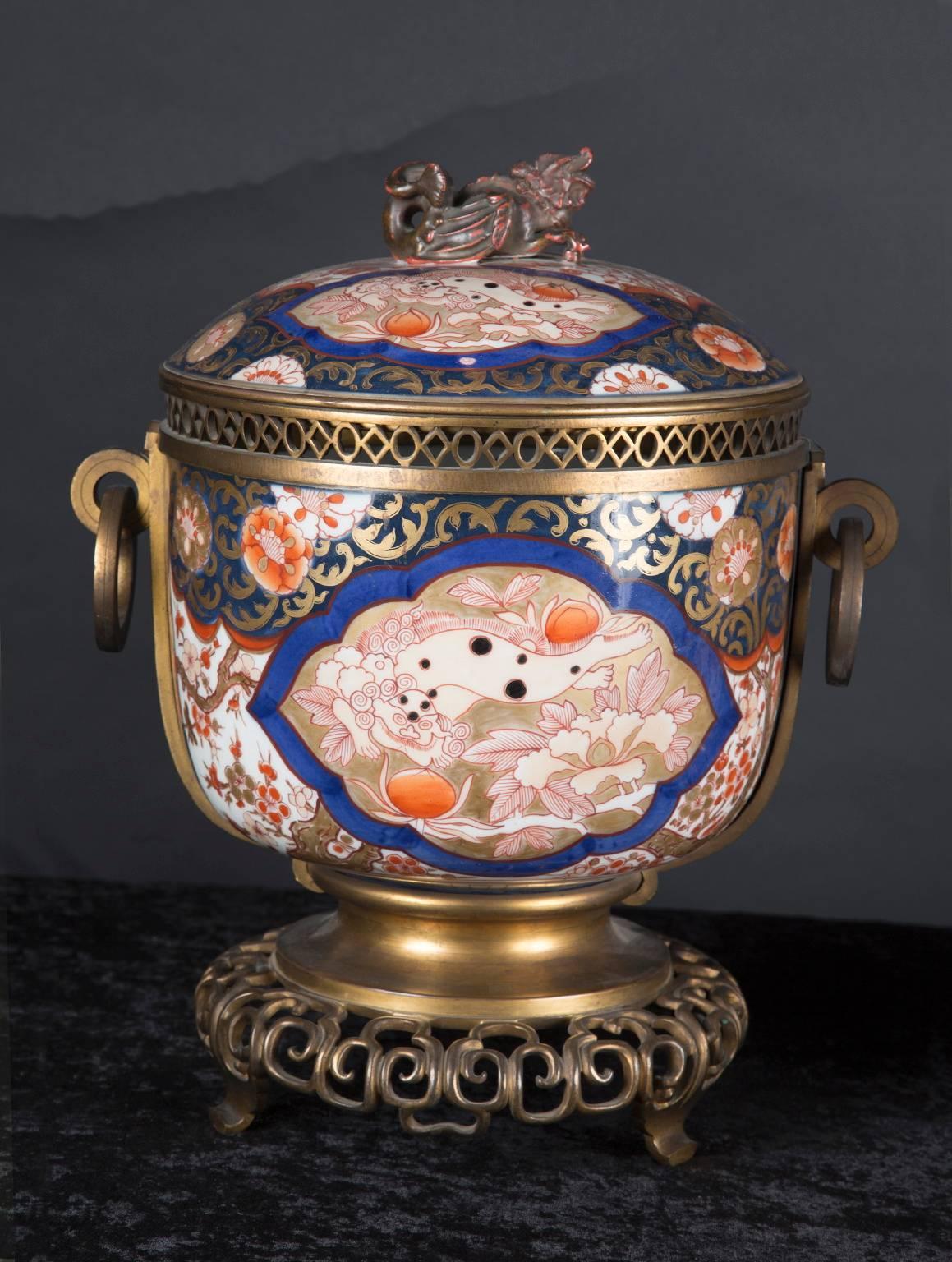 This gorgeous pair of 19th century Japanese Imari vases are beautifully hand-painted in the classic Imari colors of blue, terra cotta, gold and white. The pair features a Foo dog handle on each top, and detailed bronze work throughout. Note the