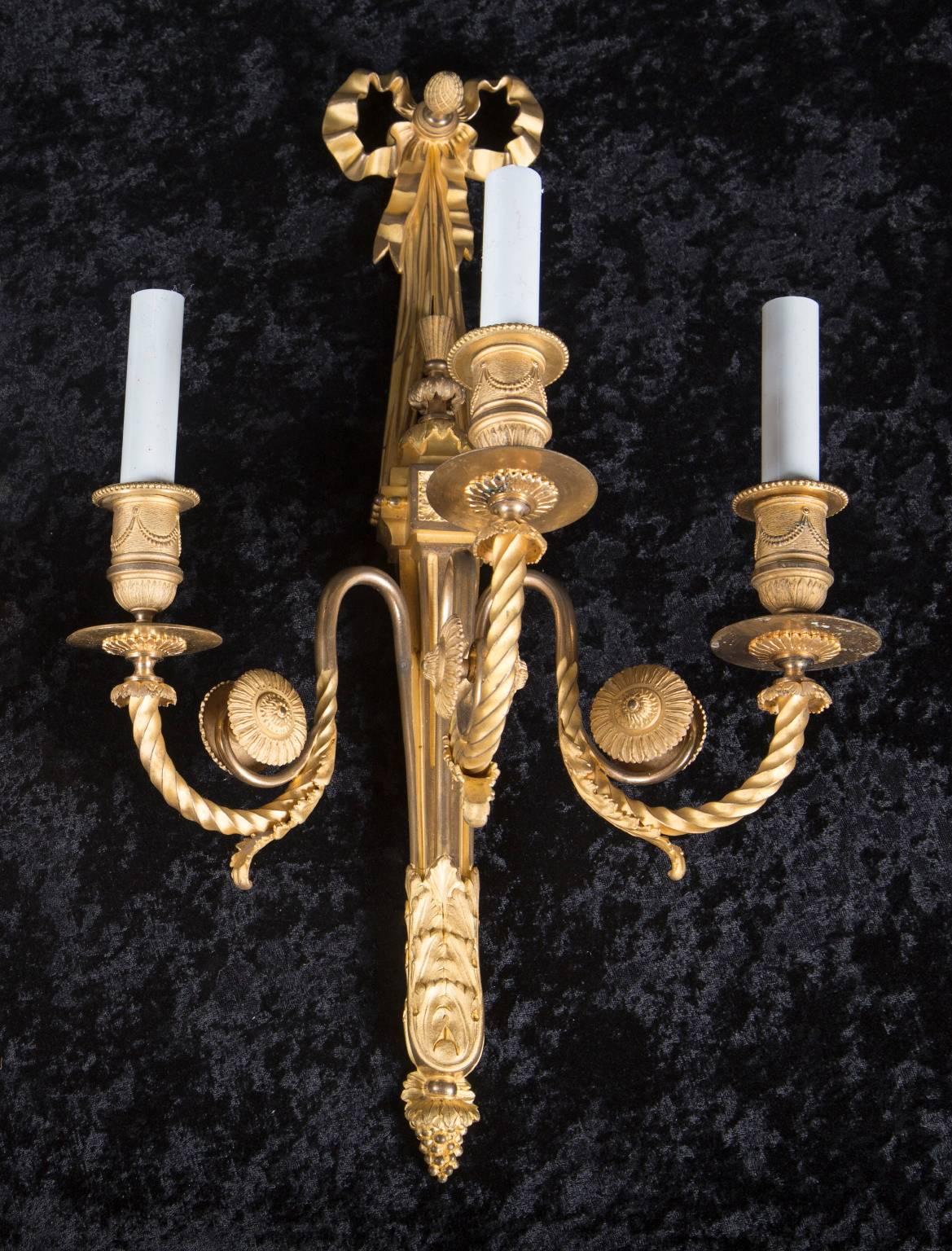 Cette paire d'appliques Louis XVI à 3 lumières, en bronze d'or fin et ciselé, date du 19e siècle. La paire d'antiquités françaises comprend des goutteurs perlés, des coupes de bougies ornées de guirlandes et des bobèches. Les bras tourbillonnants