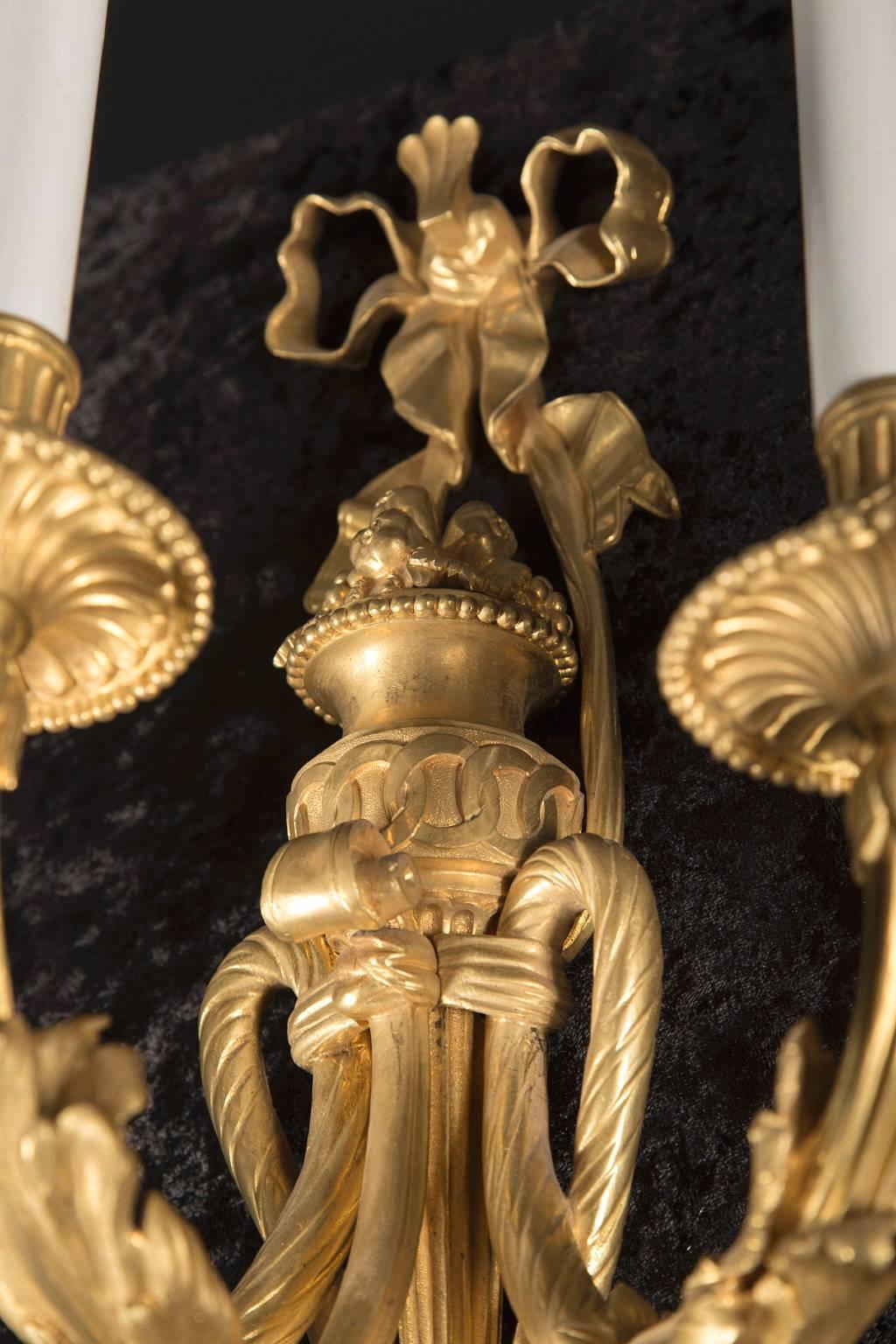 This gorgeous pair of 19th century Louis XVI sconces are made of beautiful, finely chiseled bronze d’ore. The pair has details in plenty; note the classic Louis XVI bow at top, the three branch arms attached to the center with a knotted fabric