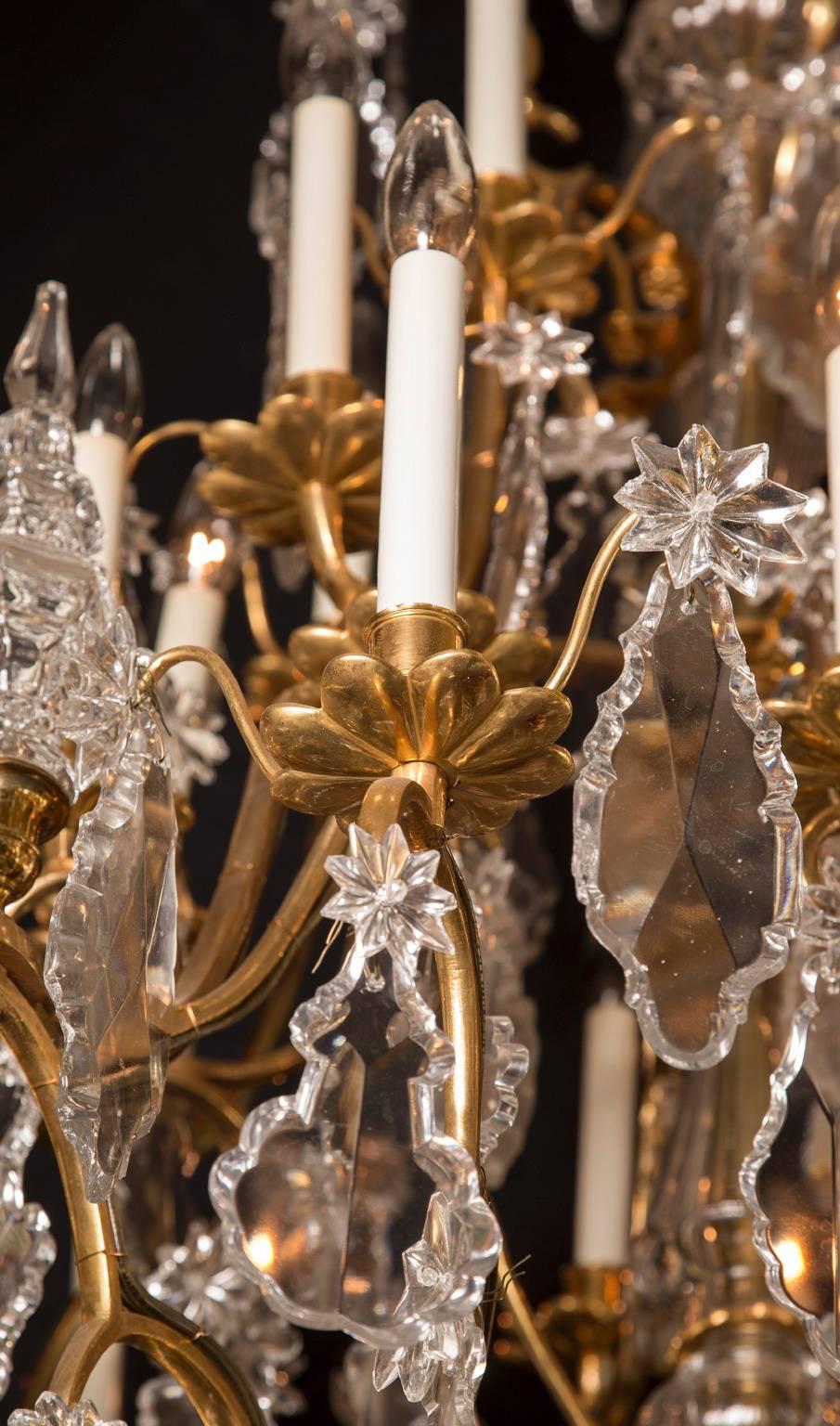 Ce lustre français Louis XV à plusieurs niveaux est fait d'un magnifique bronze d'or et date du 19e siècle. La pièce comporte 45 lumières et est ornée d'une pléthore de cristaux ; on peut voir de grandes plaquettes de différentes formes, souvent
