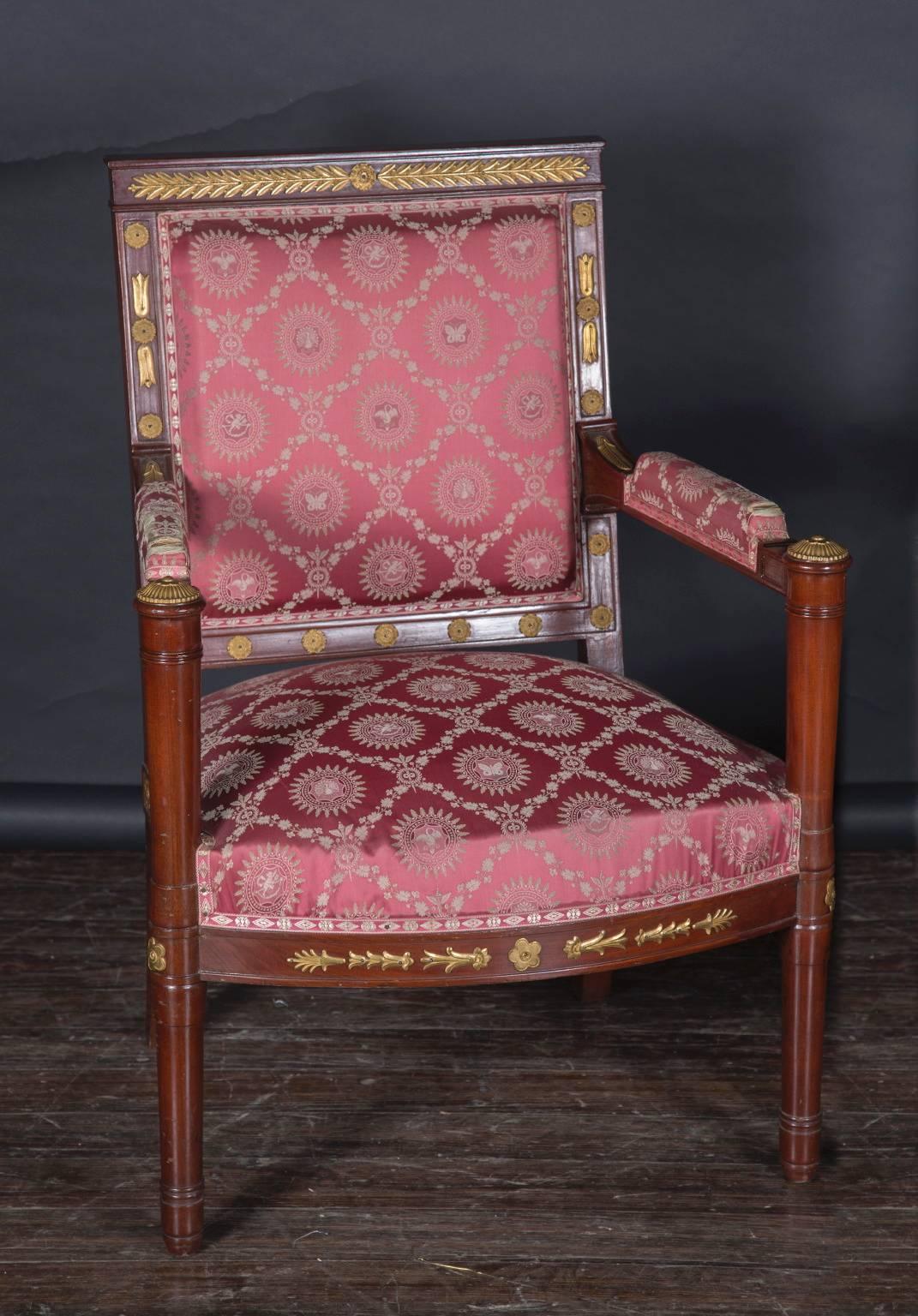 This beautiful pair of French Napoleon III open arm chairs are made of mahogany in the Empire manner. The pair dates back to the 19th century and is embellished with bronze d’ore laurel leaves and floriate d’ore mounts throughout. Note the top of