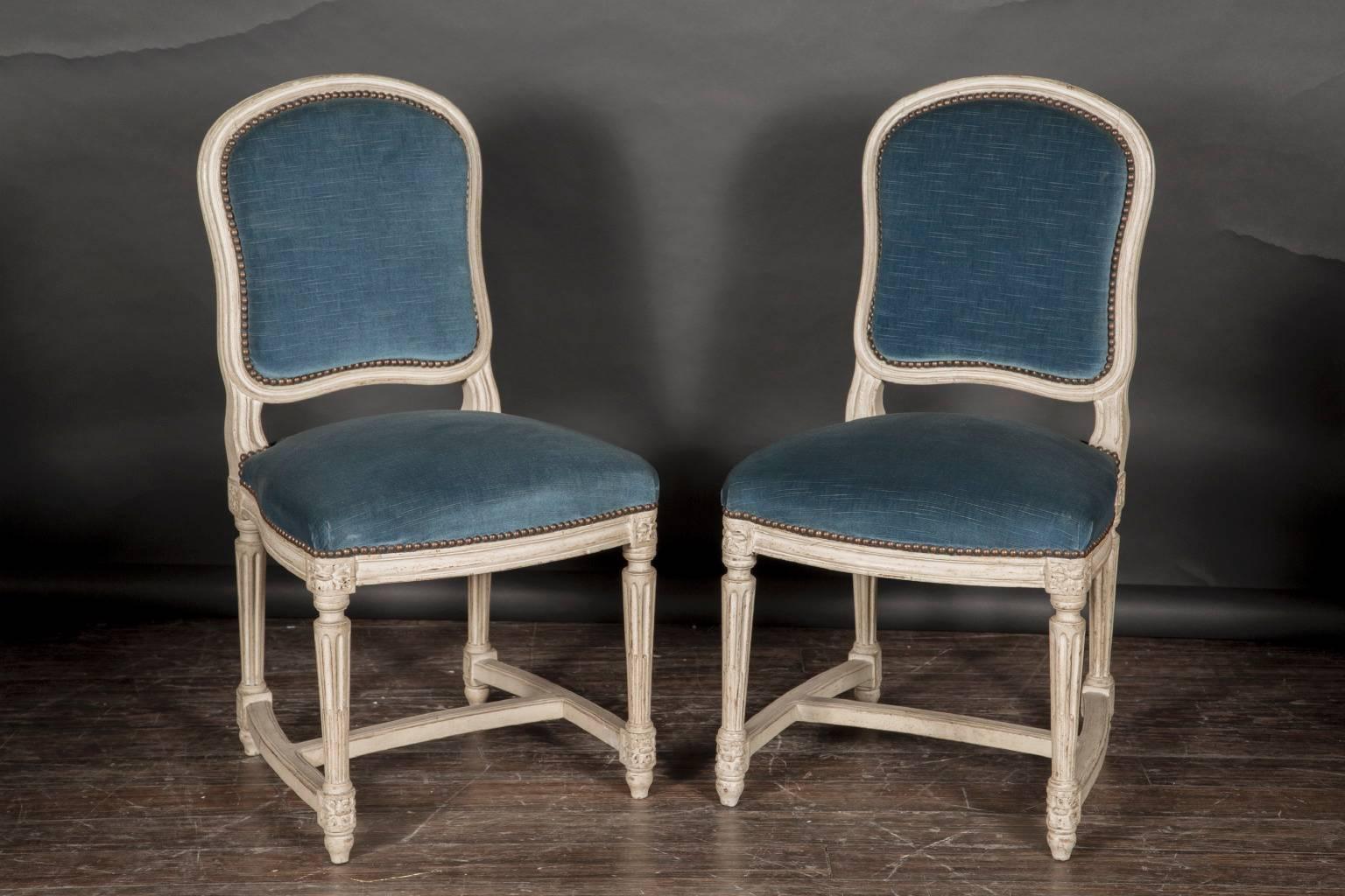 Here we have a set of ten painted side chairs from the 19th century, an excellent set to go around a table, or interspersed throughout a room. The stretchers of the chair are upholstered in blue velvet, complementing marvelously the wood painted