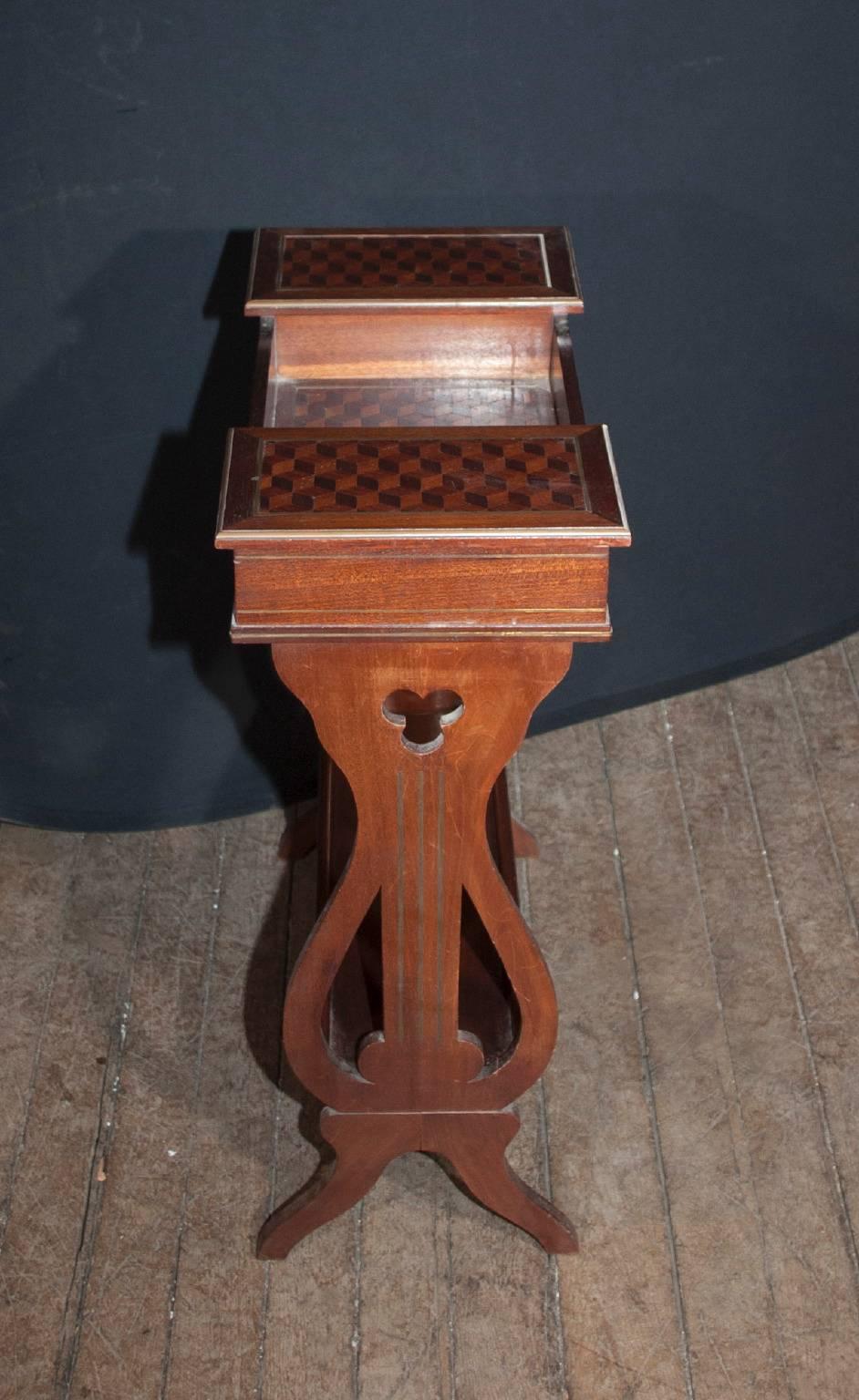 This beautiful French Restauration style table dates back to the 1800s and is made of beautiful walnut wood. The table is in the shape of a lyre, and features a top inlaid with parquetry chevron shapes, a hinged box on either side for closed