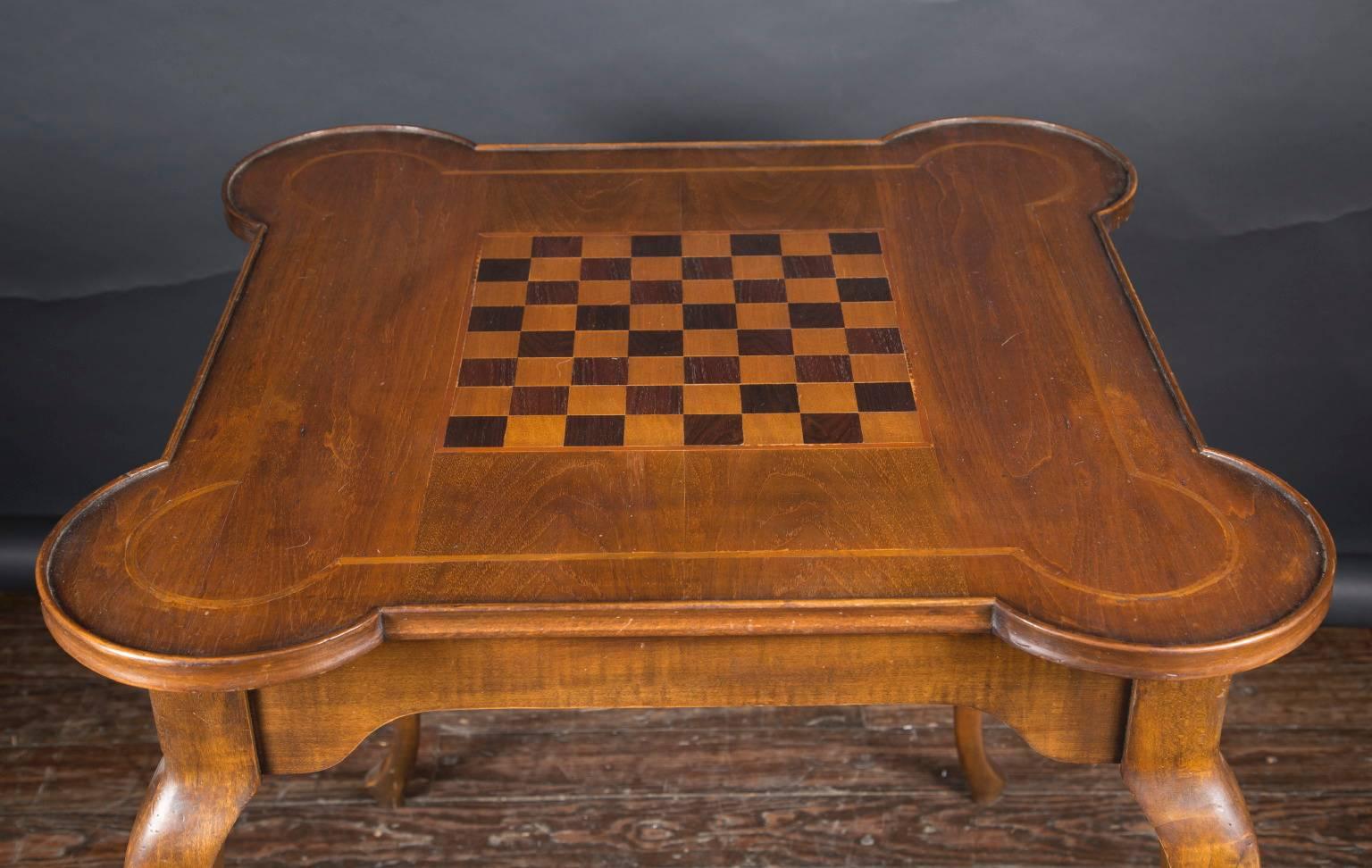 This Italian 20th century game table features an inlaid checkerboard top, a contoured banding inlay around circular curved corners and all sides, and beautifully curved cabriole legs. Its design is simple and full of movement, yielding a graceful