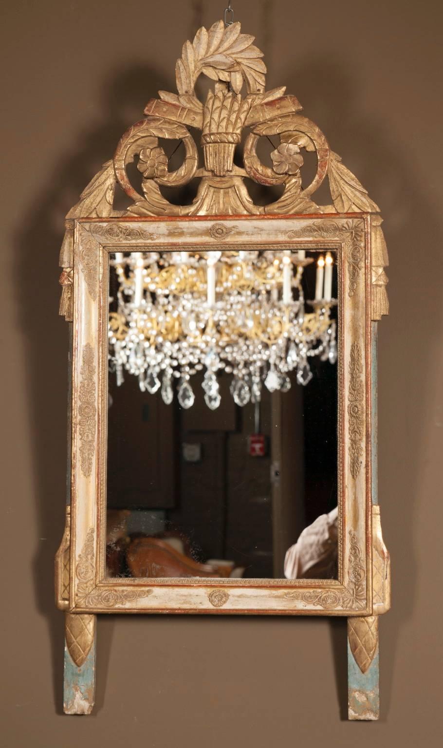 Beautifully crafted by hand in the early 19th century, this antique mirror is made of gold leaf laid over a beautiful series of carvings in a wooden frame. The frame of the mirror is embellished with various intricate swirls and designs. The bottom