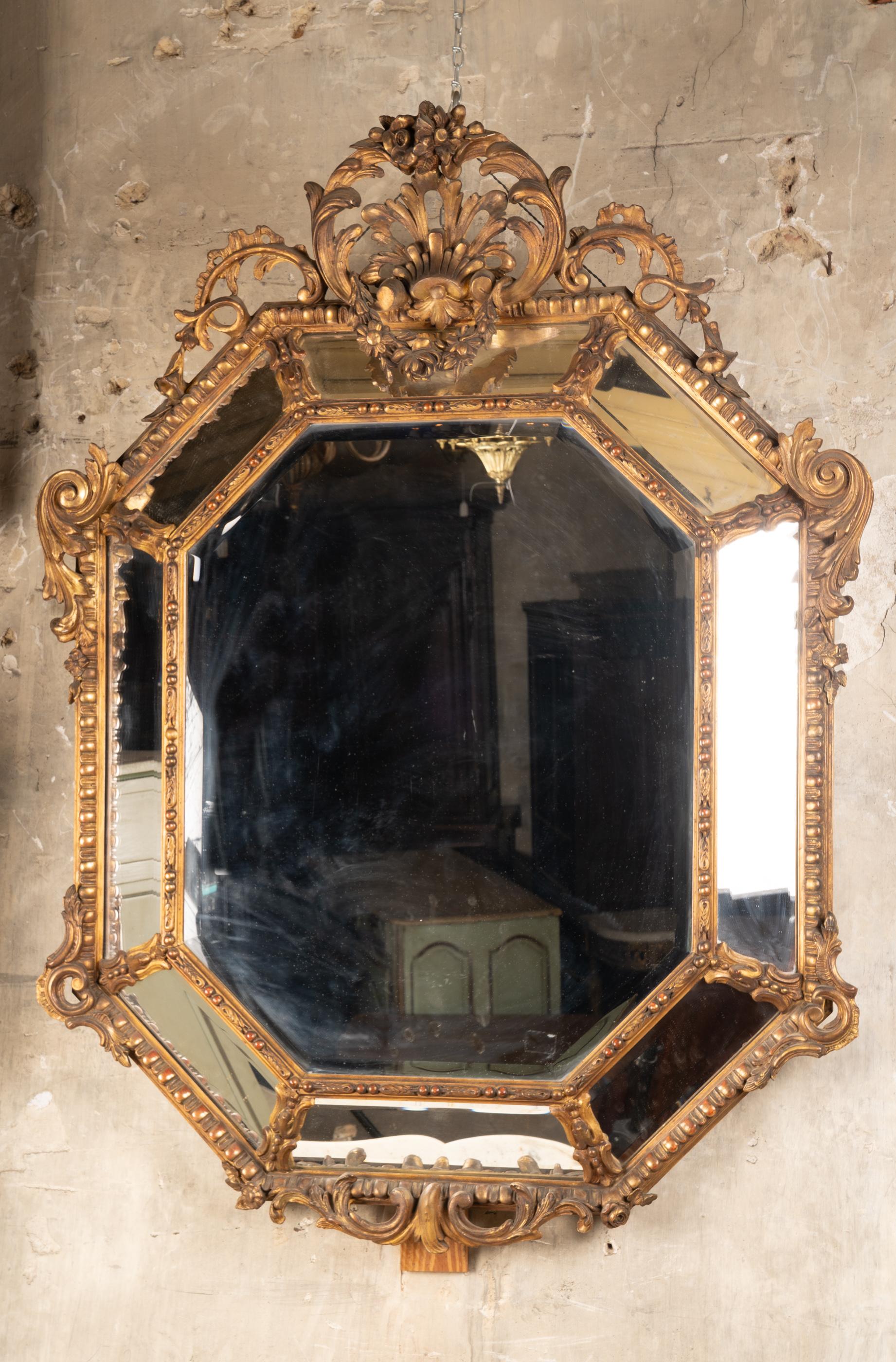 Este gran espejo octogonal data del siglo XIX y presenta un hermoso pan de oro. La madera de giltwood está tallada a mano, y el cristal está biselado en el centro y en los ocho lados del marco. El octógono exterior está elaboradamente adornado con