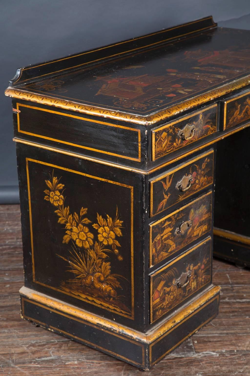 This French, 19th century Chinoiserie black lacquer and gilded kneehole desk features an impressive 9 drawer fronts decorated with flora, fauna, pagodas, and classic Japanese scene. The French antique piece sports the originl brass drawer pulls, 