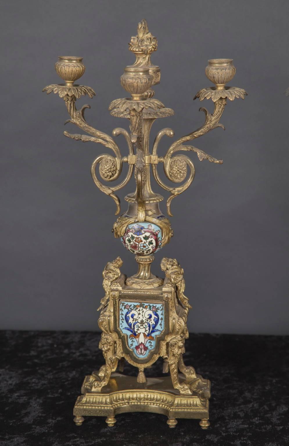 This unusual pair of 19th century three branch candelabra is made of bronze and features Champleve insets. The French antique pair is flat-backed, made to be used against the wall, as on a mantel, and has bronze candle cups and bobeches of leaves.