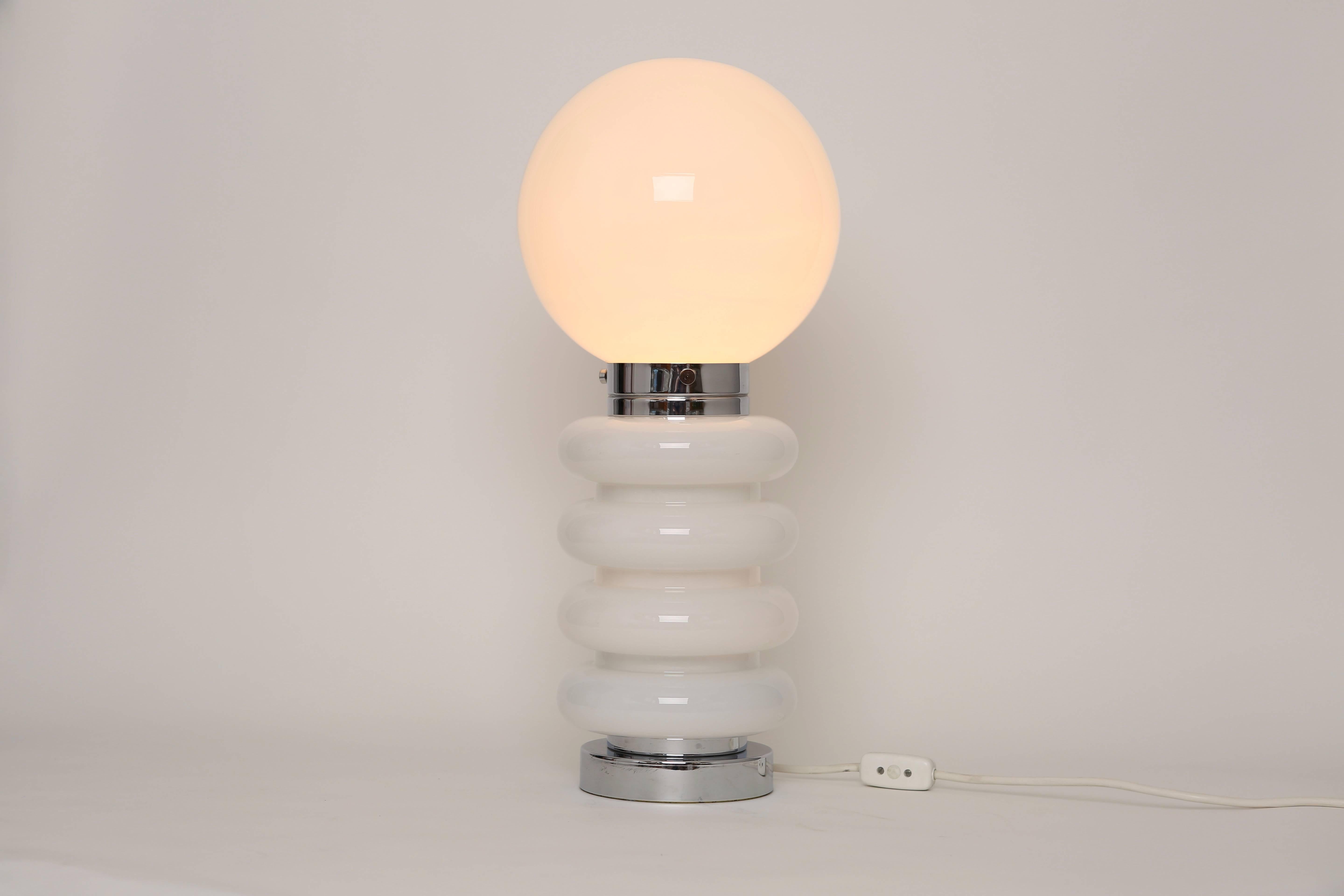 Mazzega style pair of table lamps. Made of glass and chrome-plated metal.
Lamps have three light sockets: One medium base socket on the top and two candelabra sockets at the base. When switch is on, lamps light up on the top or at the bottom, or