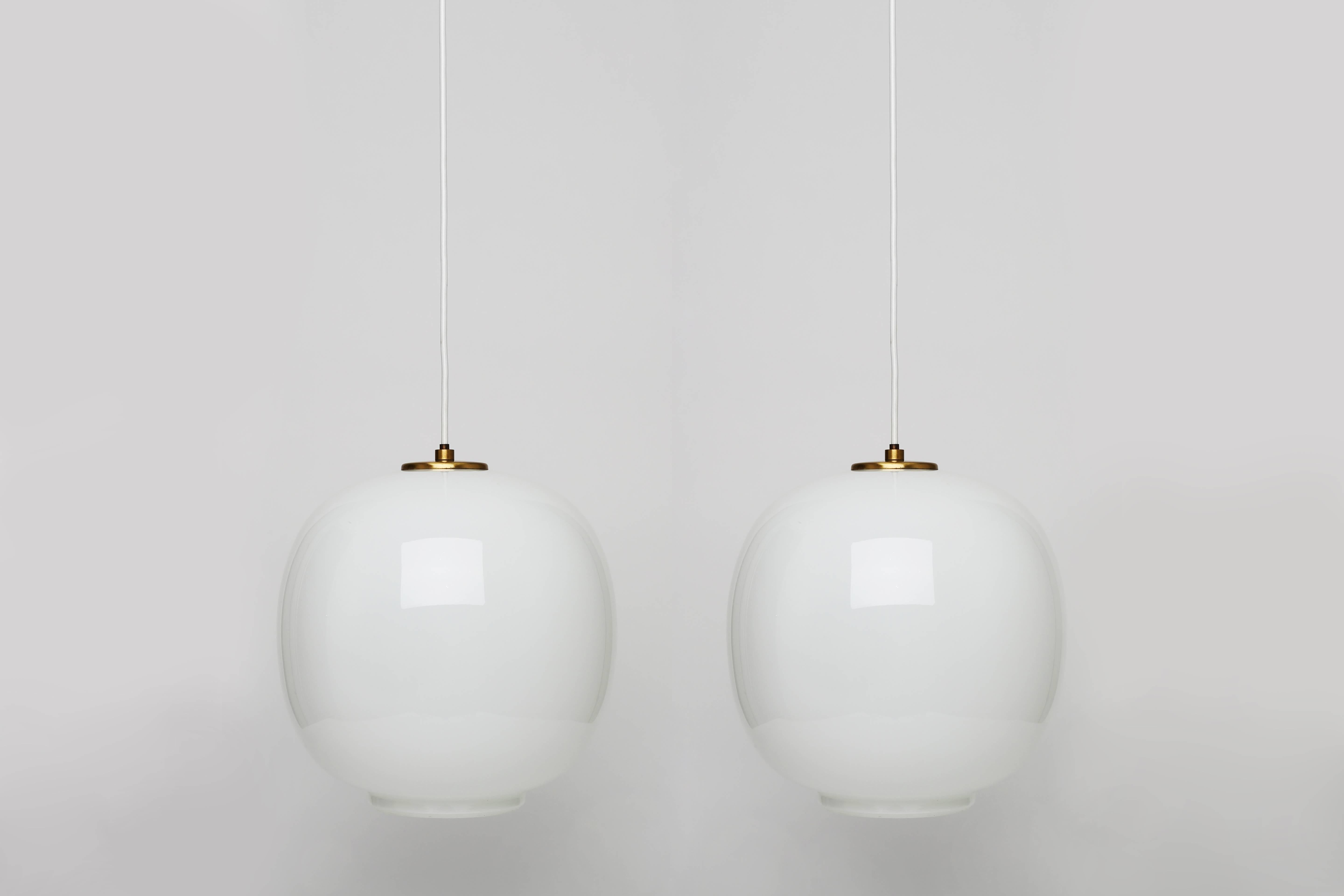 Pair of ceiling pendants by Vilhelm Lauritzen.
Designed by Danish architect Vilhelm Lauritzen for the broadcasting House in Copenhagen, Radiohouse.
Made by Louis Poulsen.
Handblown glass, brass mounts with beautiful patina.
Denmark 1940s.
Also
