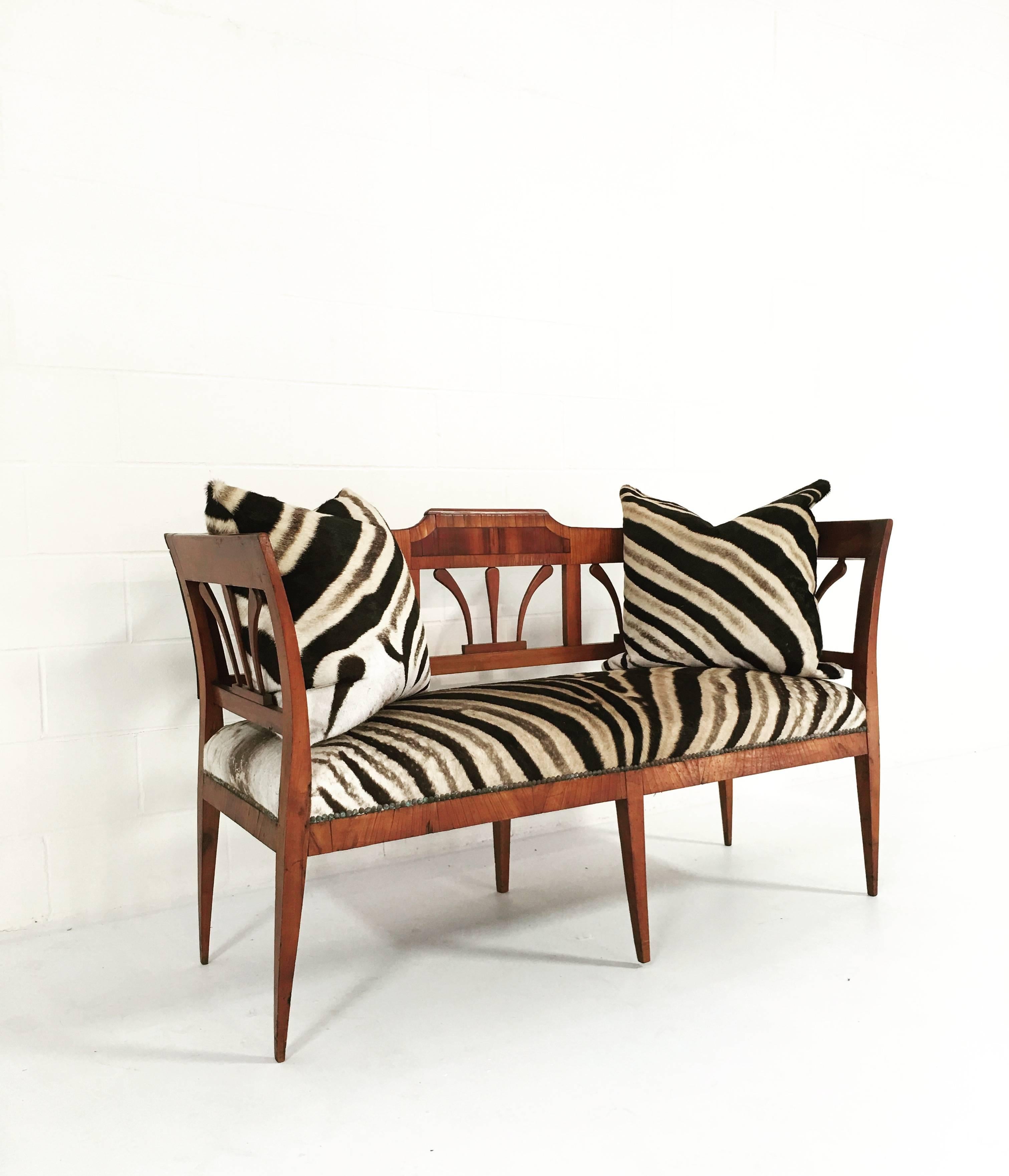 Sophistication radiates from this beautiful 19th century settee. The delicate lines of the piece are what set it apart. We designed two 24-inch down-filled, double-sided zebra hide pillows for an inviting feeling of high style and luxury. It is