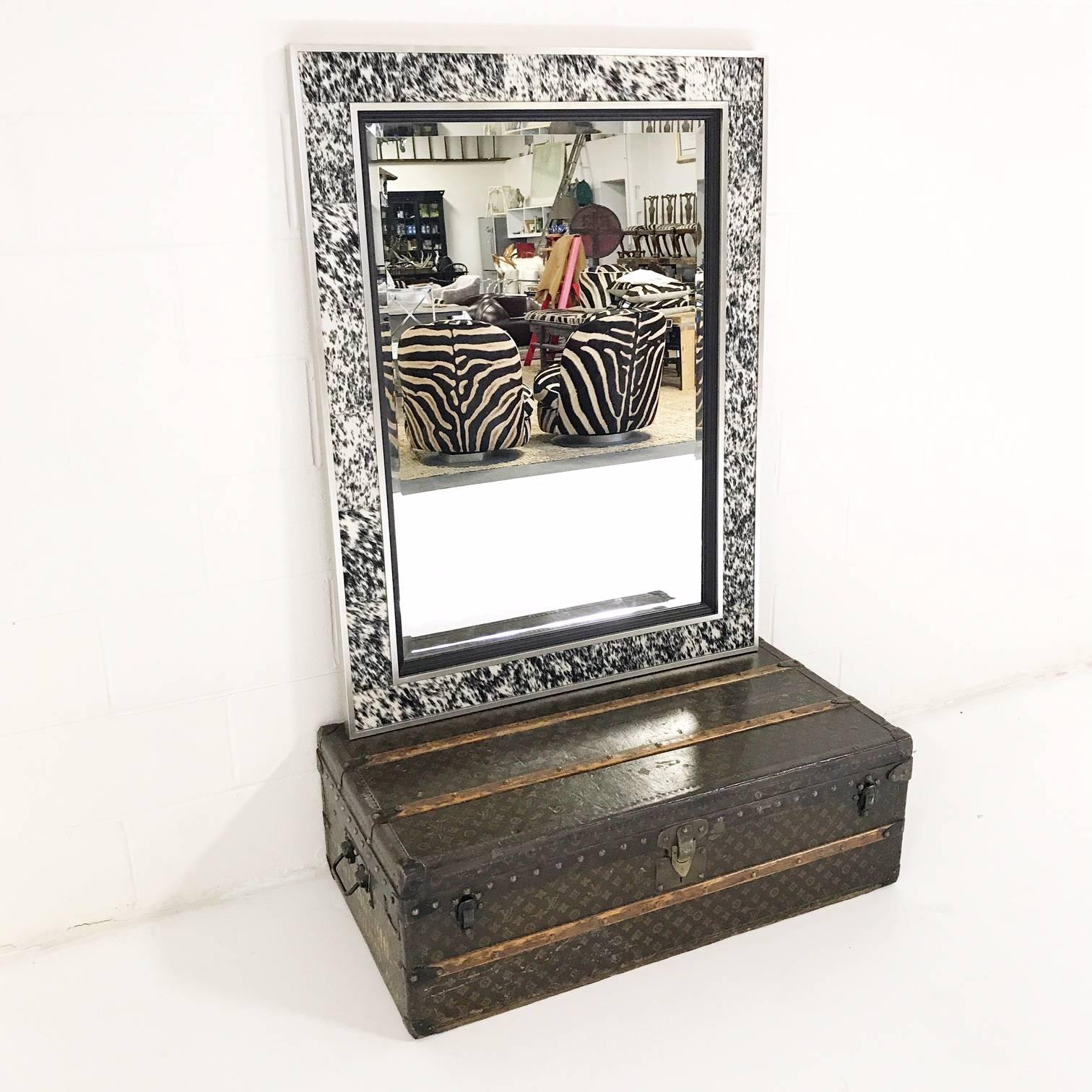 The black specked cowhide and silver finished frame pack a glamorous punch in any room. The beveled mirror adds sophistication and brilliance. Beautiful!

Details:
36 inches wide x 48 inches high 
100% natural cowhide
Ready to hang.