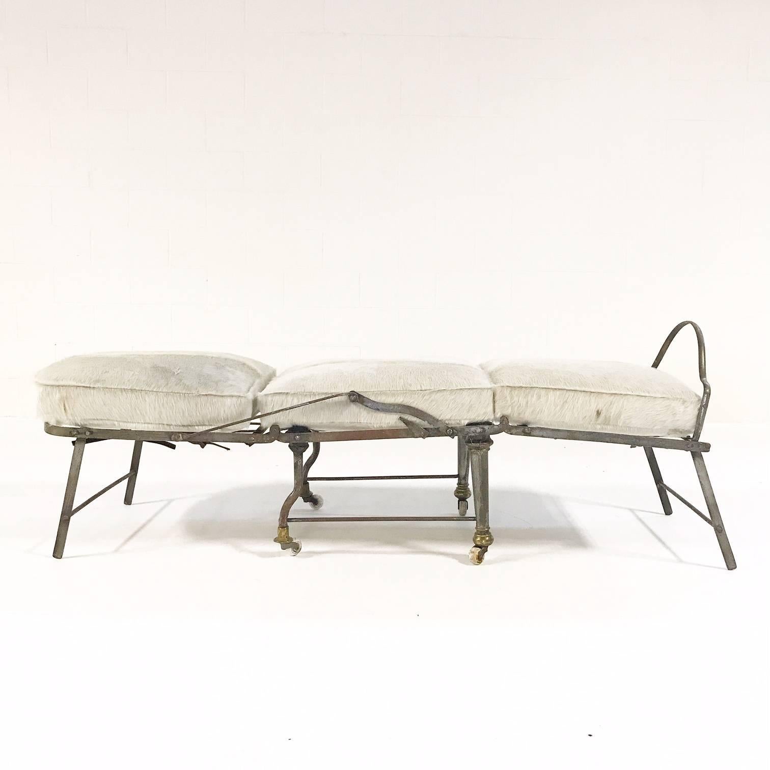A beautiful antique metal campaign chaise lounge from France. The chaise can be positioned into three different positions - as a chair, a traditional chaise, and a flat daybed. We custom made three cushions from our gorgeous ivory cowhide. Each