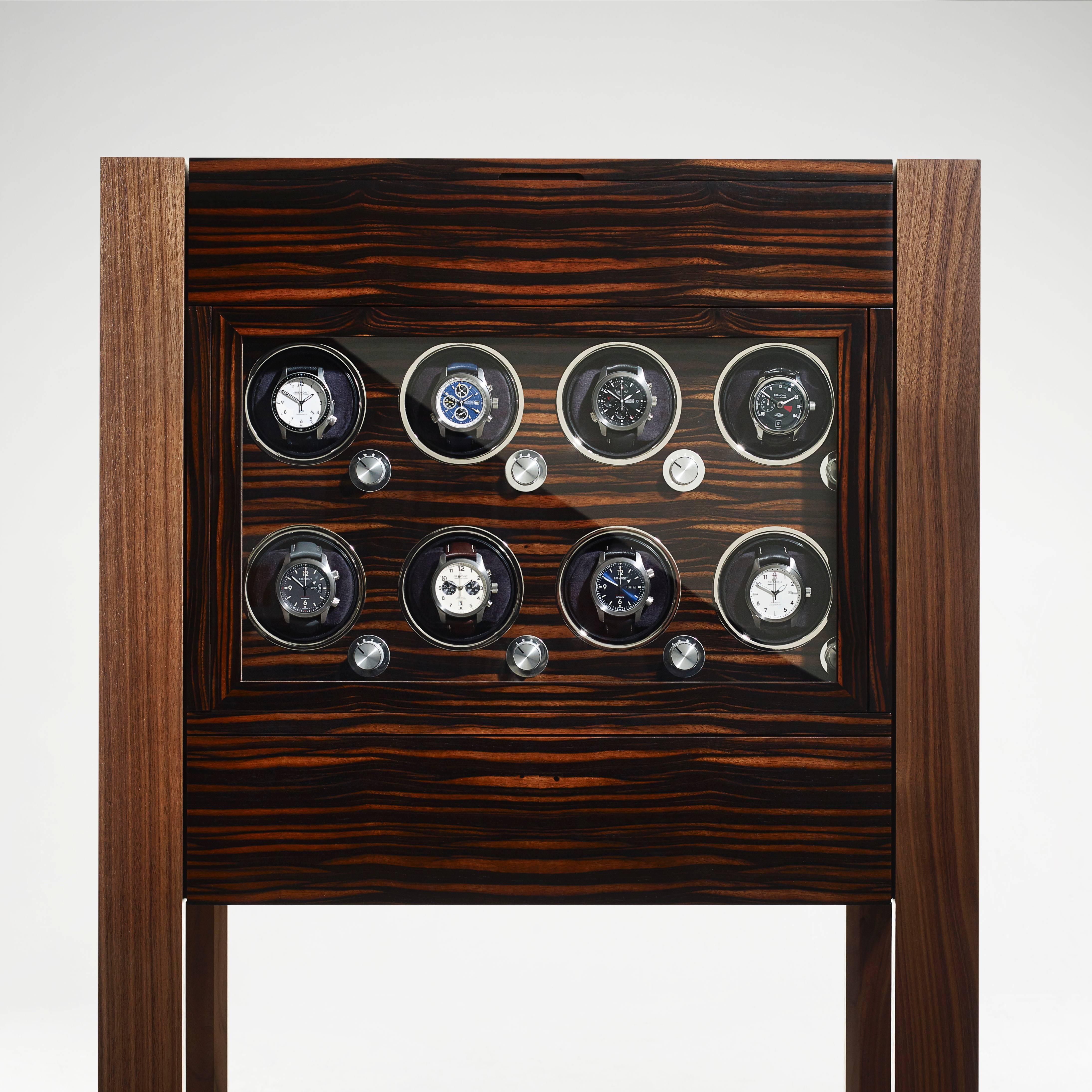 Handcrafted in marble Macassar ebony and walnut with a ripple walnut interior. Eight watch winders for keeping automatic watches ticking are displayed behind a hinged glass door at the front of the cabinet, with leather lined compartments, padded