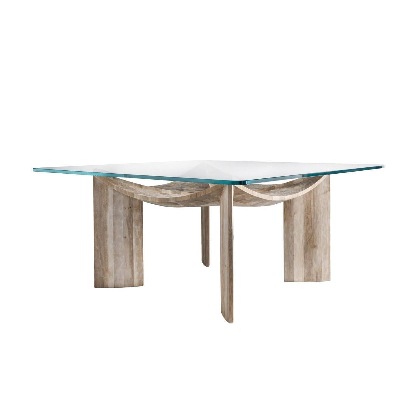 The solid Italian walnut wood of this imposing table is hand-carved with a gouge. The top glass rests on four crossing legs in the shapes of sails blown by the wind.