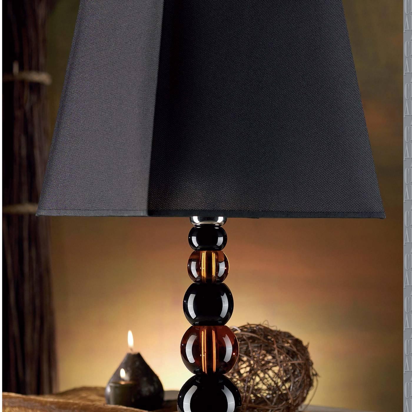 This elegant lamp has a body crafted completely in crystal and is constructed by mounting alternating spheres in opaque black and transparent brown crystal on top of one another. This piece has a clear base and a black lampshade.