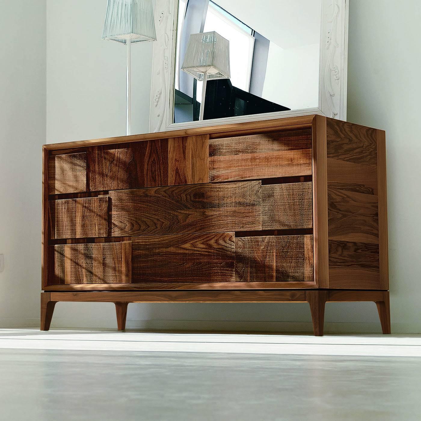 This elegant chest of drawers in walnut wood fillet features three solid walnut wood drawers with panels adorned with a striking geometric decoration of solid walnut wood and a finish that can be in natural oil or natural grey oil.