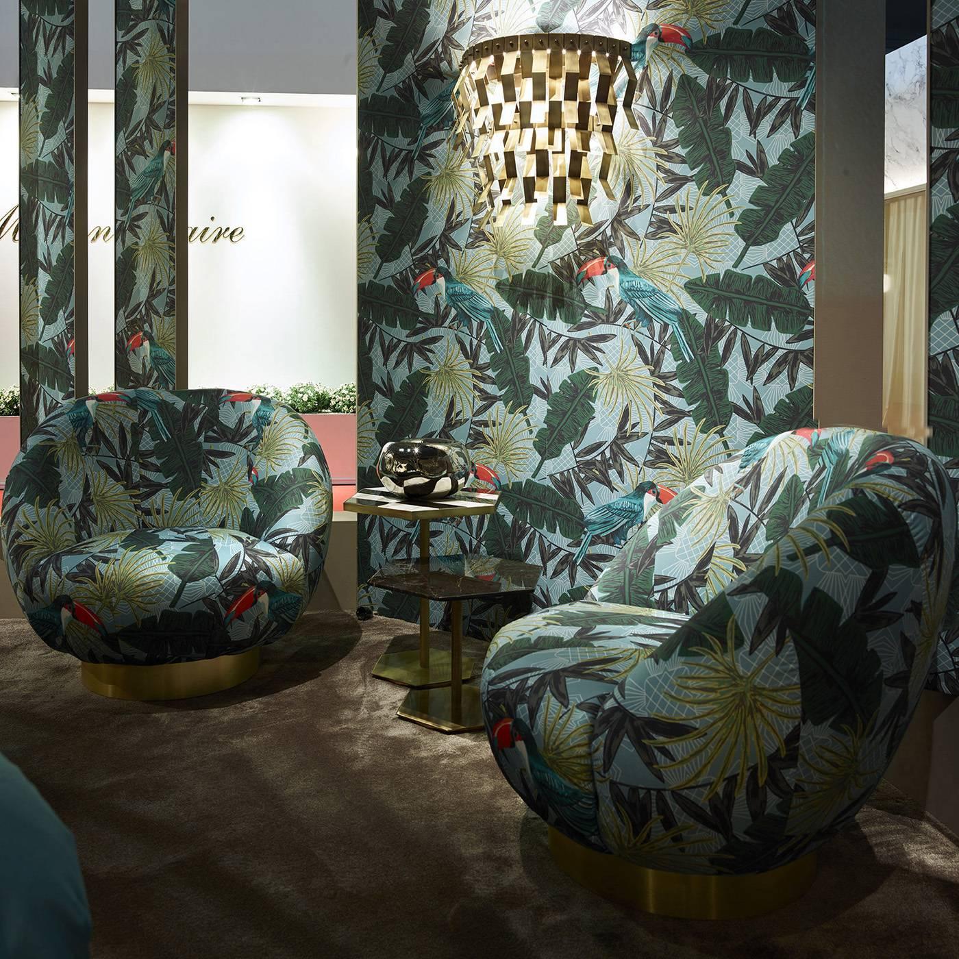 This swivel armchair features a metal structure and can be upholstered in different fabric or leather. In this configuration, the cover is in fabric with a tropical print.