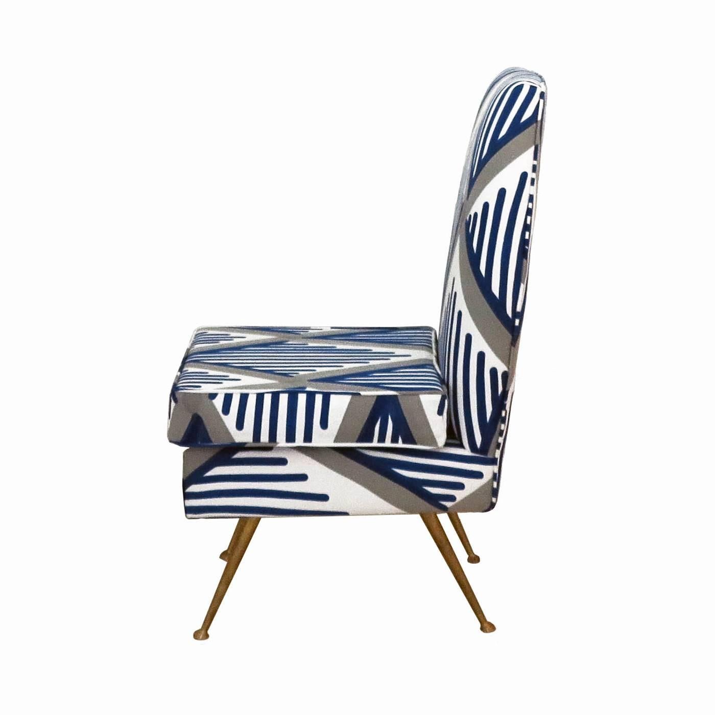 This elegant chair has a wood structure with brass feet. Its chair and seat are covered in 100% cotton decorated using the pigment printing technique with a geometric pattern of thick grey diamonds and blue parallel lines over a white background.