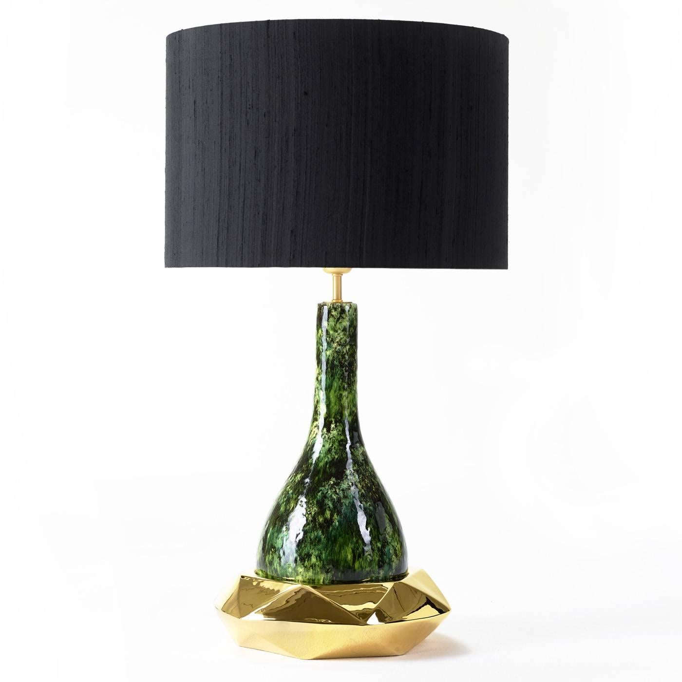 This striking table lamp has a ceramic body finished in ghost green lacquer resting on a multifaceted metal base. It comes with its shade.
