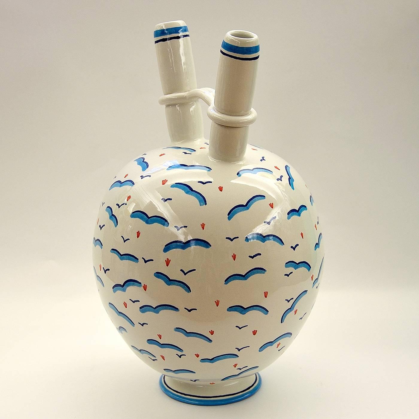 This uniquely shaped ceramic vase, with two necks, was made on a lathe and enameled in earthenware. It was beautifully decorated with blue, light blue, and red hand-painted designs depicting seagulls in mid flight, over a shiny white base. This