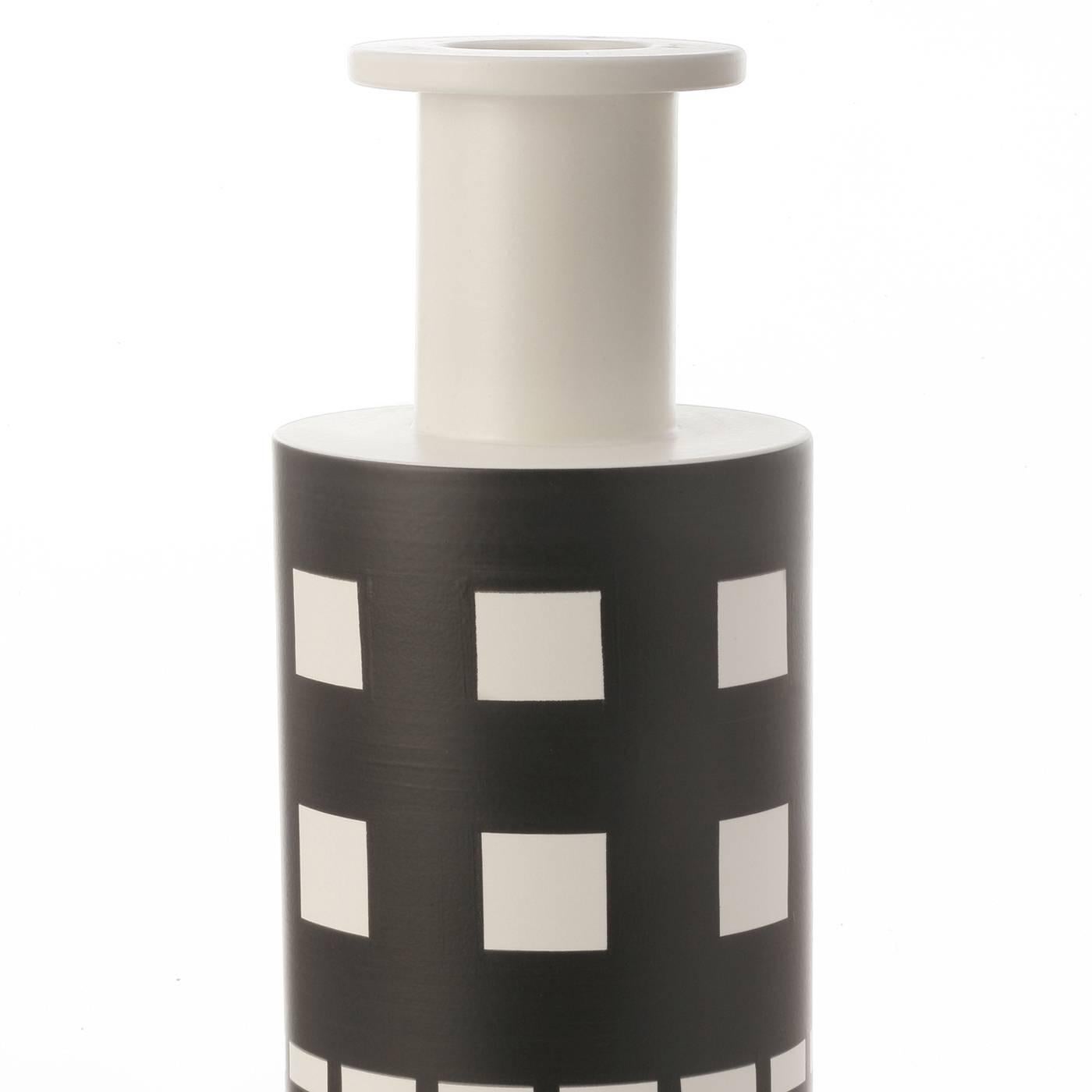This vase's simple shape is complemented by its geometric decoration that features striking motifs in black on the white background of the cylindrical shape. This piece was designed by renowned architect Ettore Sottsass in 1962.