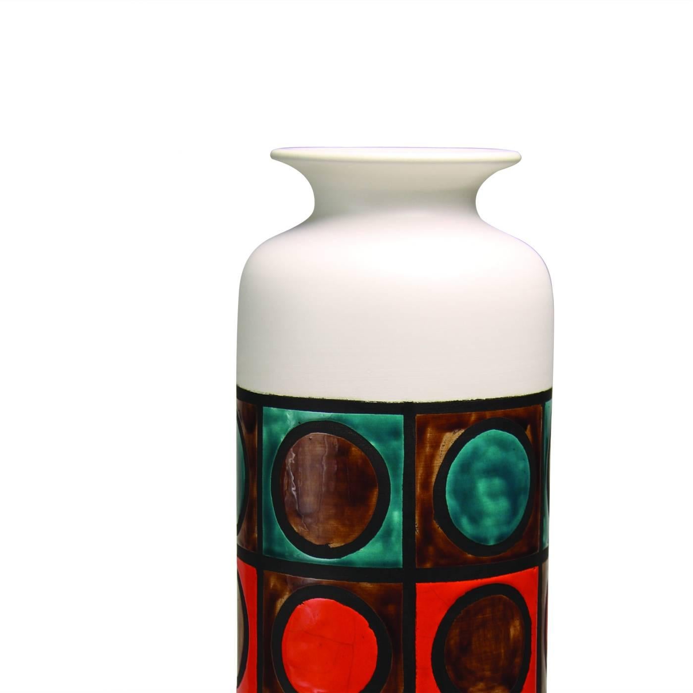 This striking vase in white clay has a simple cylindrical shape with a white finish, and a central area decorated with a series of multicolored rings enclosed in squares each marked with a dark edge. This piece, designed by Aldo Londi in 1963, is