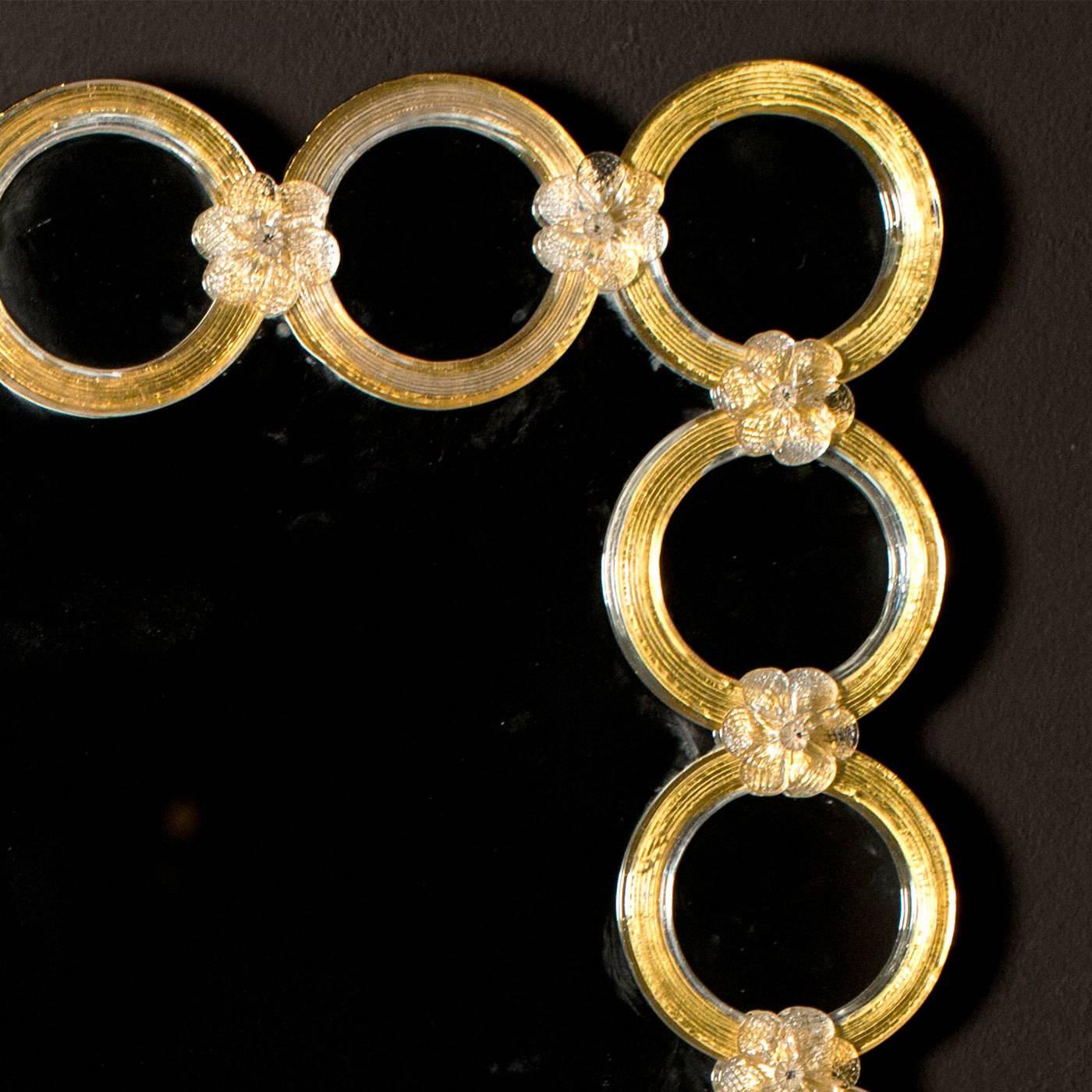 Goldene Ringe aus Muranoglas schmücken diesen rechteckigen Spiegel von Ongaro e Fuga. Das Dekor ist durch Glasblumen, die die einzelnen Ringe miteinander verbinden, mit der Holzgrundplatte verschweißt und vermittelt so einen Hauch von Tradition in