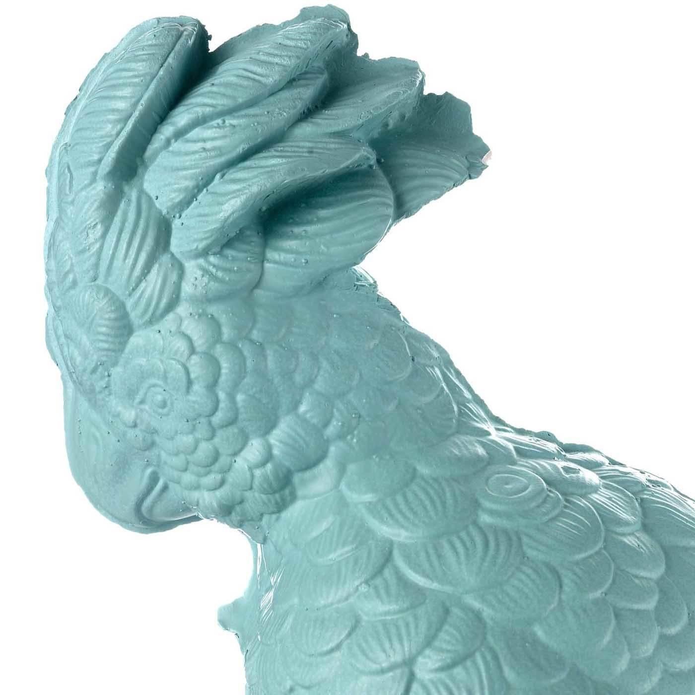 This striking decorative object reproduces a parrot in all its vivid details. The bird is perched on a blooming pedestal and has a magnificent crest of feathers on its head. The Fine ceramic used to create this piece has a precious satin finish and