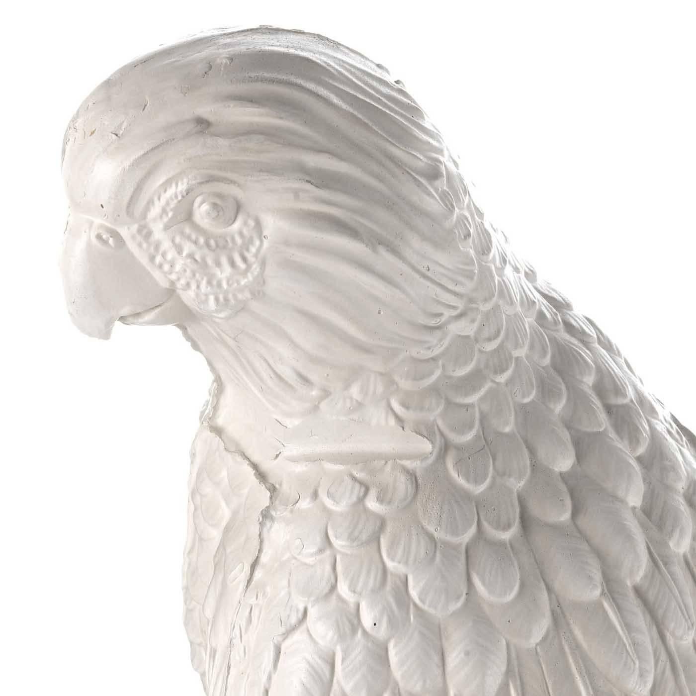 This playful parrot was entirely made in ceramic using artisanal methods that feature a mold that is manually filled with liquid clay to obtain the life-like features of the bird and the details of its plumage and head. The parrot is perched on a
