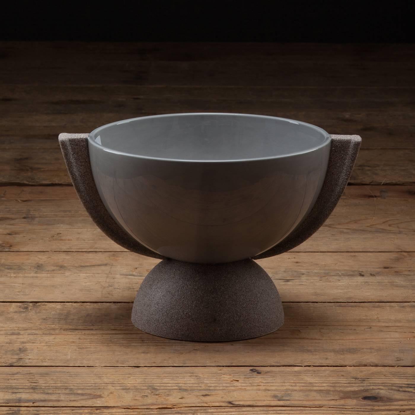 This exquisite and versatile piece combines two different textures: the semi-spherical body with a polished finish, and the base and two small handles with a opaque, sand-like appearance. The grey hue of this cup blends it with any decor.