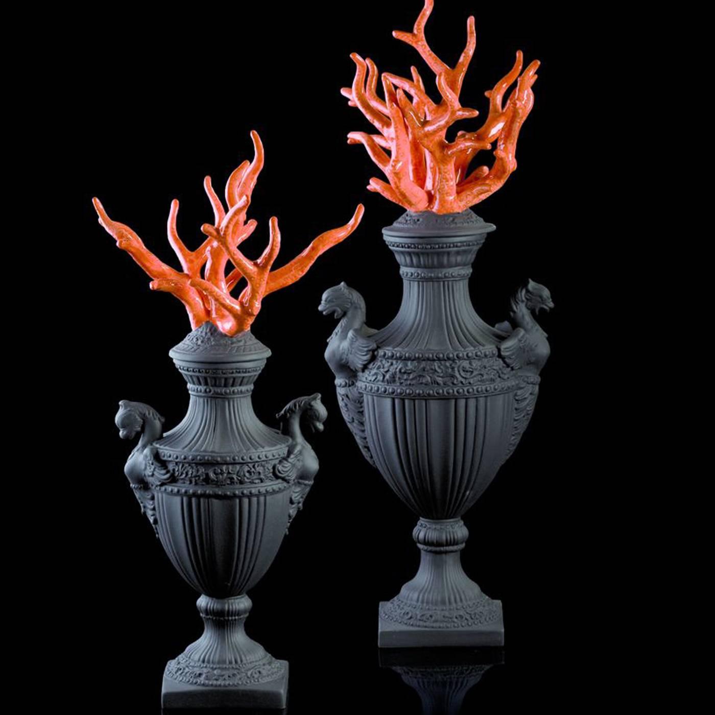 This elegant piece is made of an elaborately Baroque vase with a matte black finish and featuring two marine-inspired figurines on its sides. The lid is strikingly decorated with branches of coral in vivid red ceramic with a polished finish.
