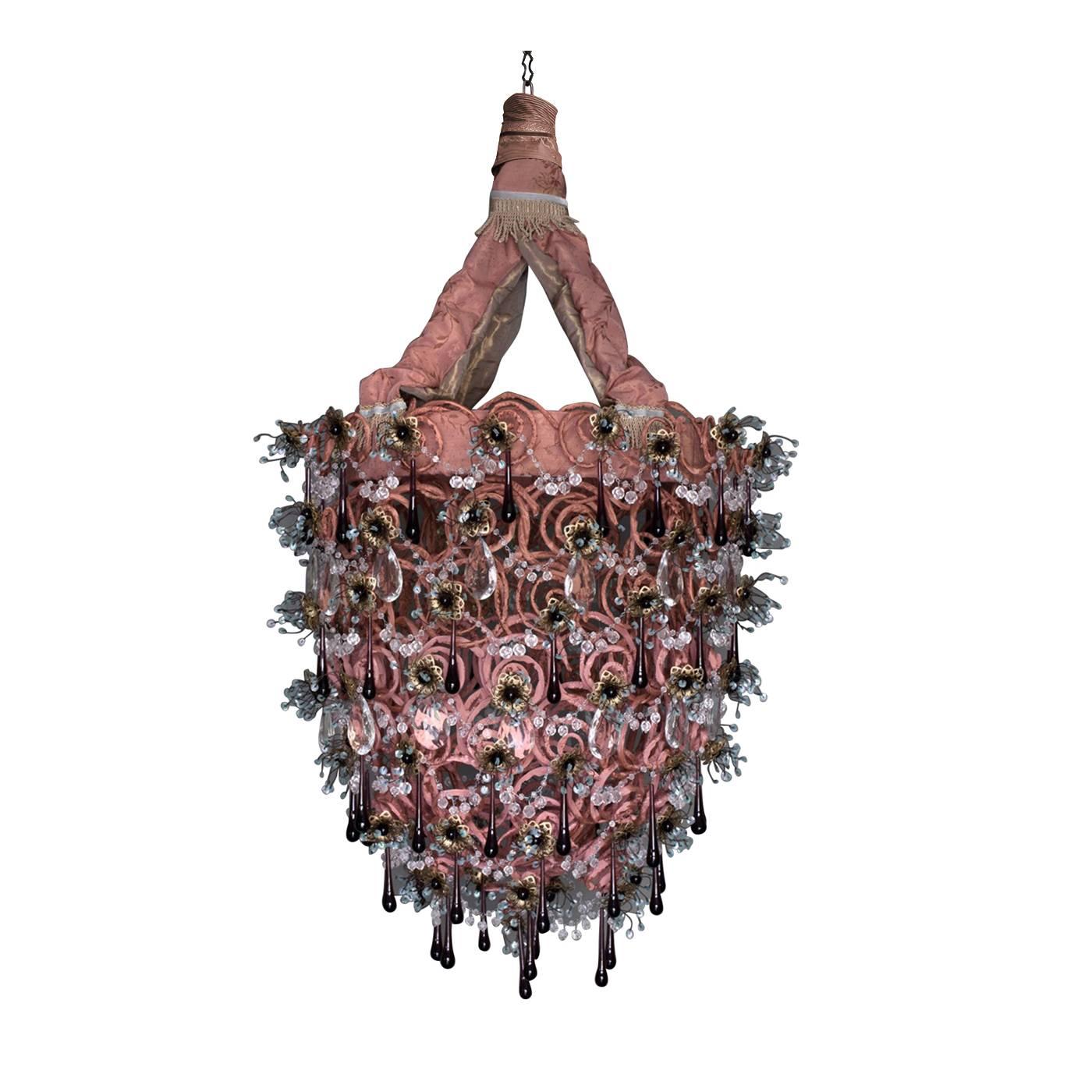 Trimming, glass, iron, sequins and delicate brass flower decorations adorn the iron structure of this object d'art that is comprised of 99 meters of spirals covered with a double layer of soft pink velvet.