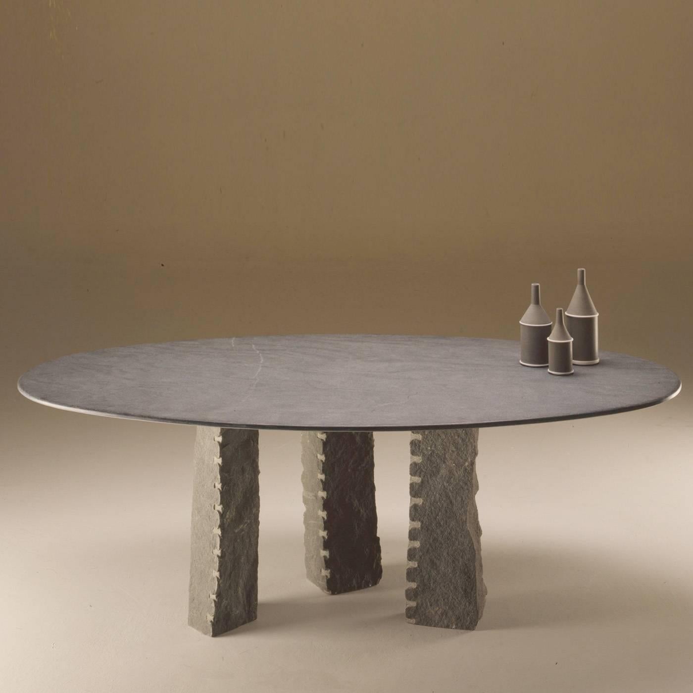 This powerful, impressive table features sandstone hand-sculpted and chiselled legs and an oval tabletop made of polished diorite. The legs are removable. The entire table is gray.