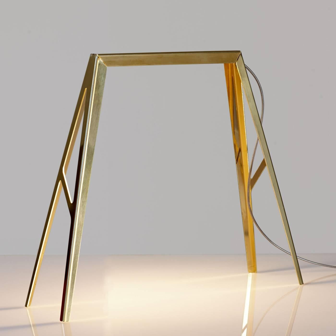 This unique lamp is crafted using brass sheets that have been cut by lasers and later bent to achieve this striking shape that resembles a bridge whose top hides a LED strip. The natural glow of the brass can attract light even when the lamp is not