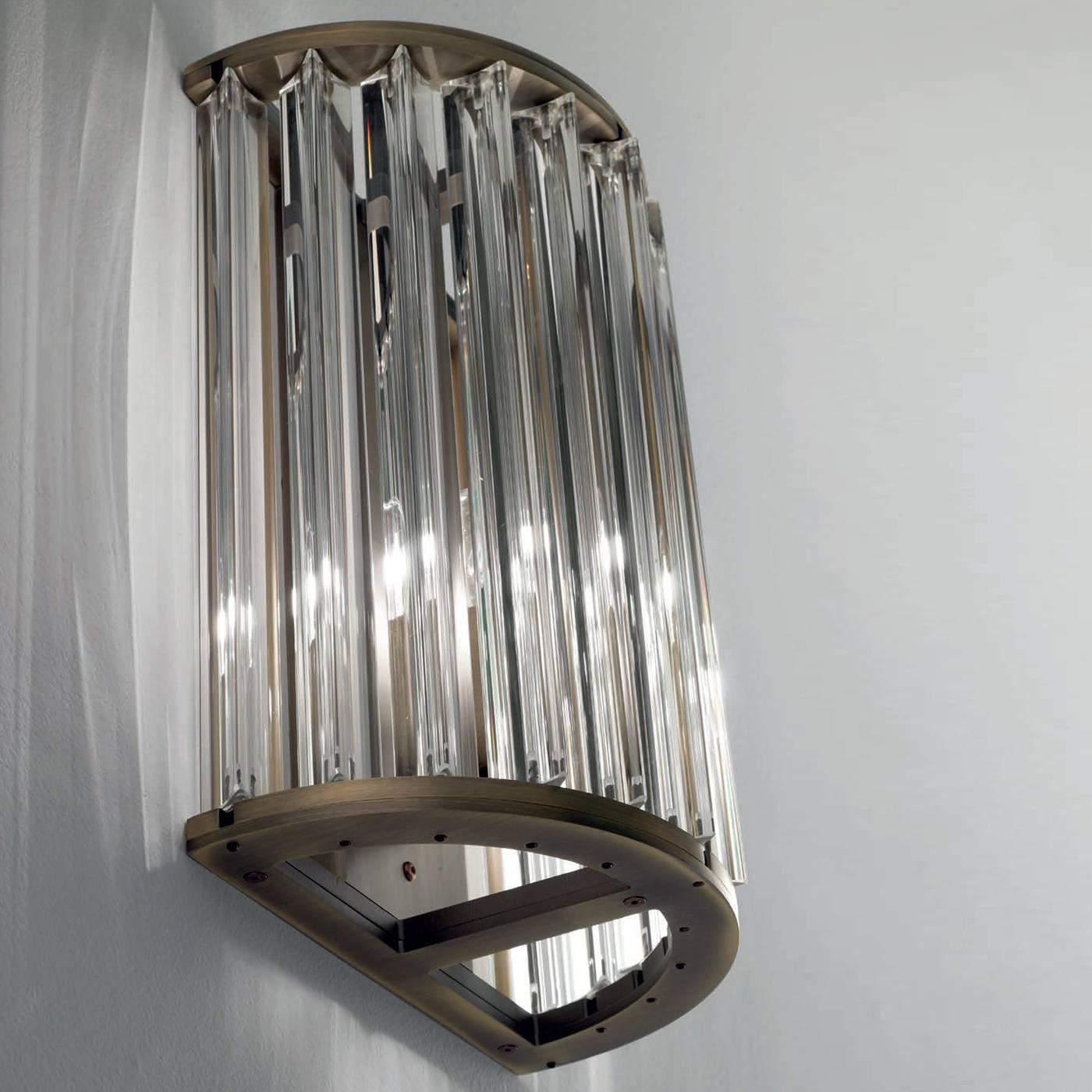 This exquisite sconce exudes art deco elegance and old-fashion sophistication, thanks to its triangle-section rods of crystal placed in a semi-circle and brilliantly diffusing the light for a timeless effect. Particularly suitable for a classic