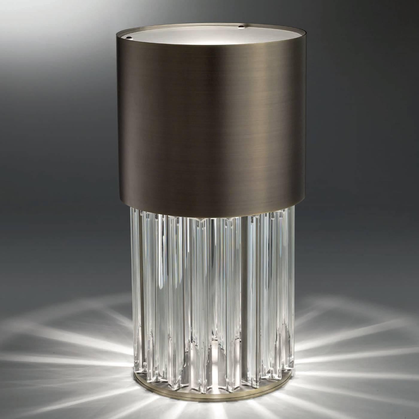 The sophisticated allure of this light comes from its precious materials and timeless lines that make an elegant and timeless Silhouette in the shape of a luminous cylinder with a dark bronze structure on top, supported by a series of trihedrons