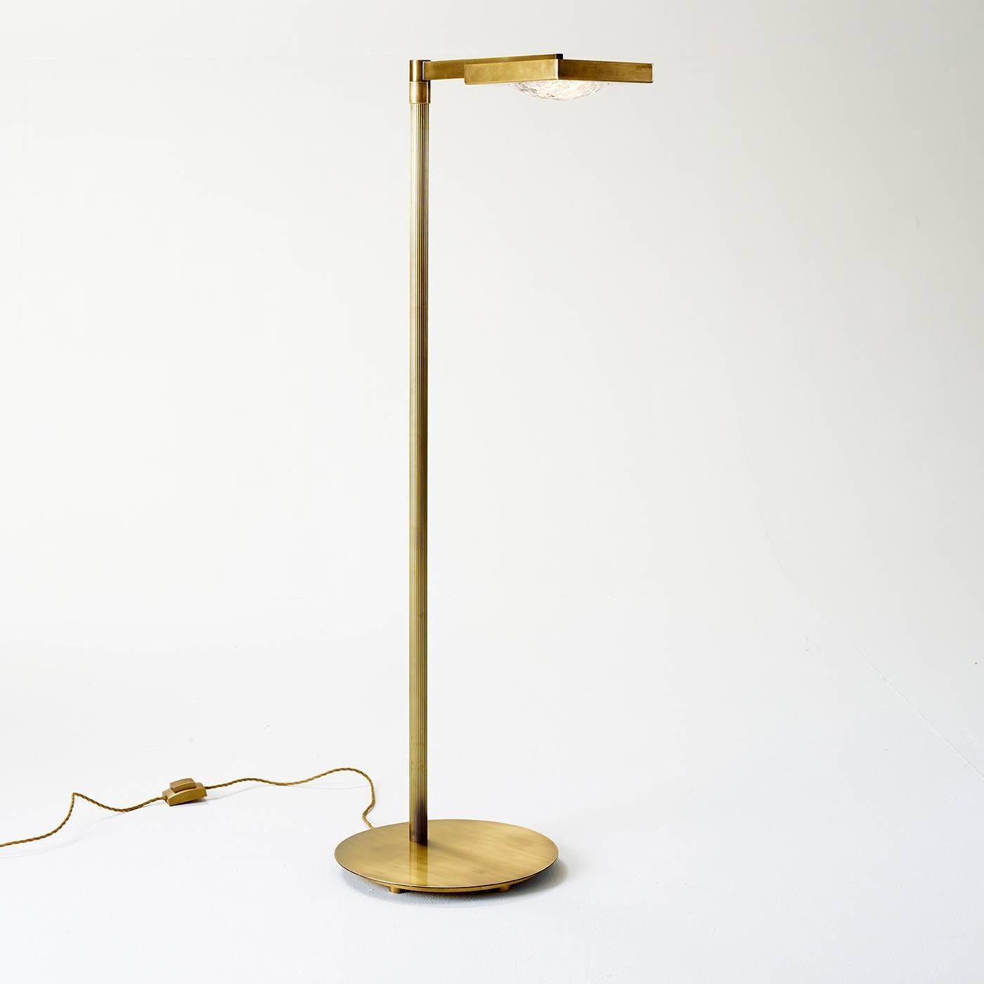 This golden floor lamp by Marioni is primarily made of brass, and is adequately fitted with an adjustable bridge arm on the top, as well as a polycarbonate lens, and a light diffuser that gives an ice effect to the light.