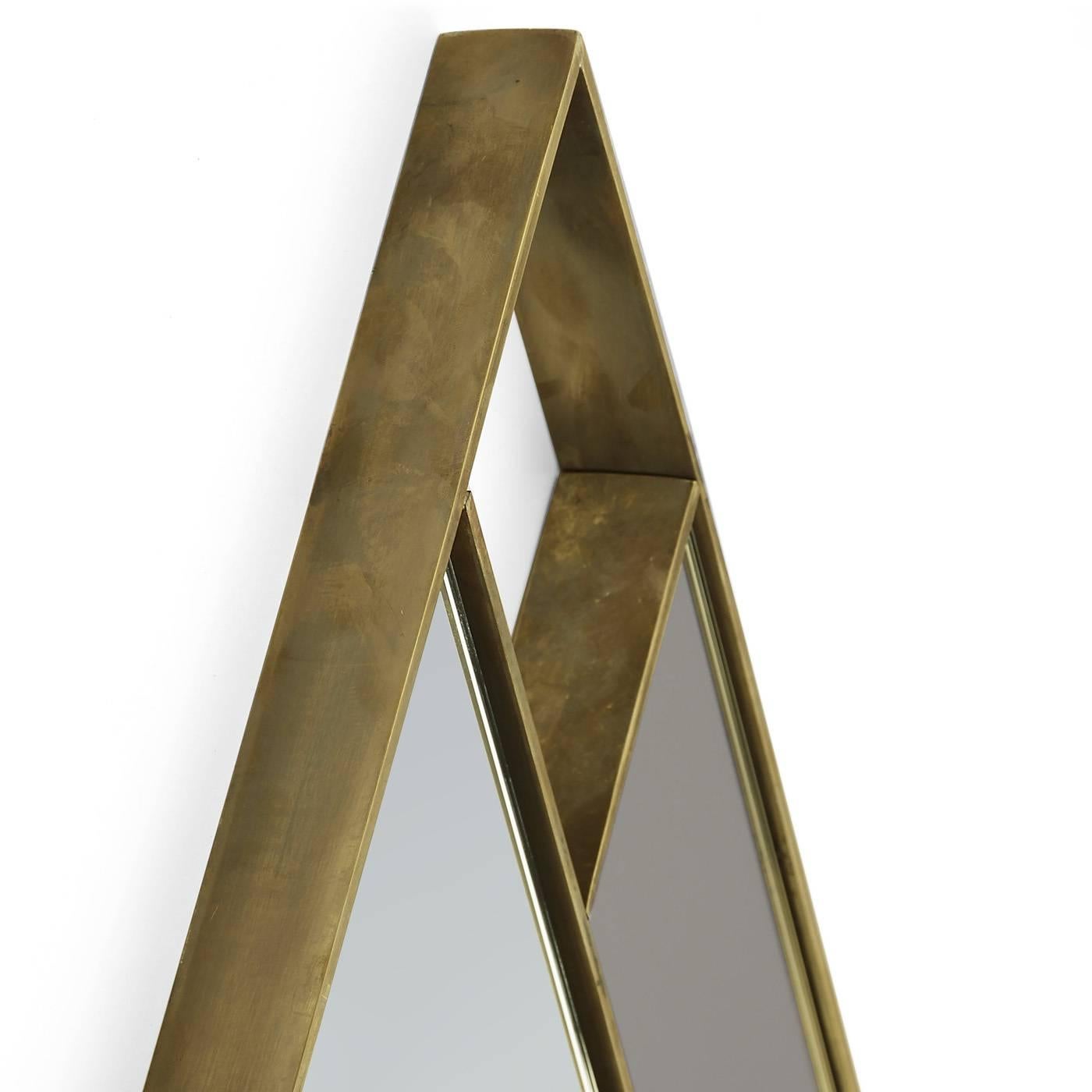 This decorative mirror has a striking diamond shape with a frame in brass and a side accent in a slightly darker shade of glass.