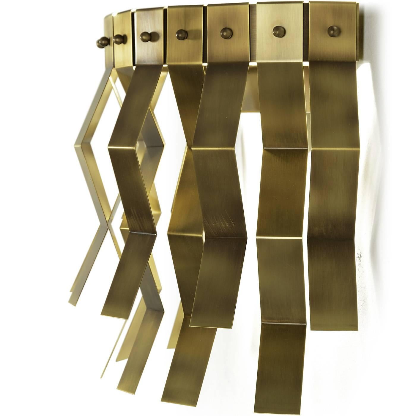 This striking brass sconce, designed by Studio 63 for Marioni, is decorated with geometrical metal accents that run all around its round perimeter and LED strip lighting.