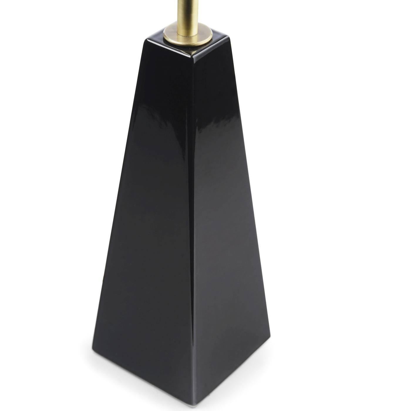 The base of this elegant lamp, designed by Studio 63 for Marioni, is a pyramid in black ceramic. The body is in brass with a cylindrical diffusor that features a decoration of vertical ridges.