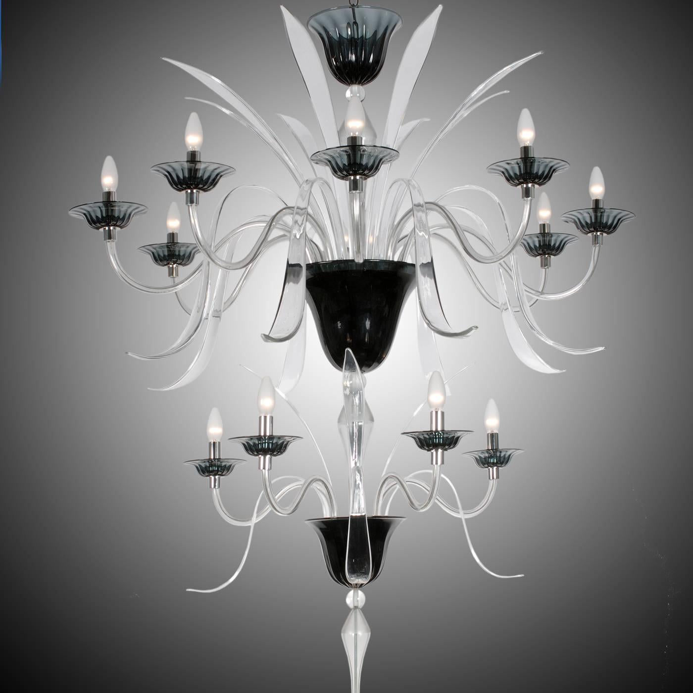 This elegant chandelier in mouth-blown Murano glass features two tiers for a total of twelve lights. Each tier is supported by a black glass upside-down cone, while the finely executed arms are in clear glass. Each of the lights is resting on a fine