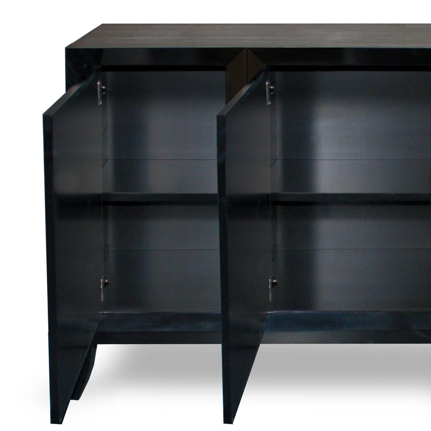 This four-door sideboard, is beautifully crafted by the finest Italian artisans and is finished in a hard, super sleek black gloss lacquer. The carved wooden leaf shaped handle, with the intense effect of the hand-applied silver leaf, offers a