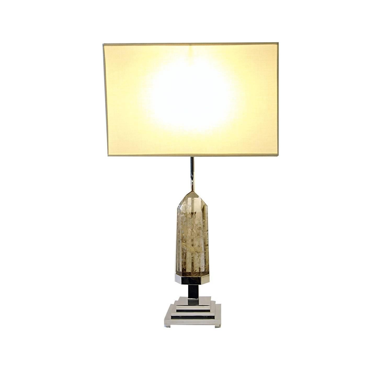 This lamp is perfect for adorning a living room, bedroom or even a sophisticated office environment. An irregularly hand-cut piece of light Smokey Quarts is Elevated on a pyramid like structure in nickel plated brass which was meticulously