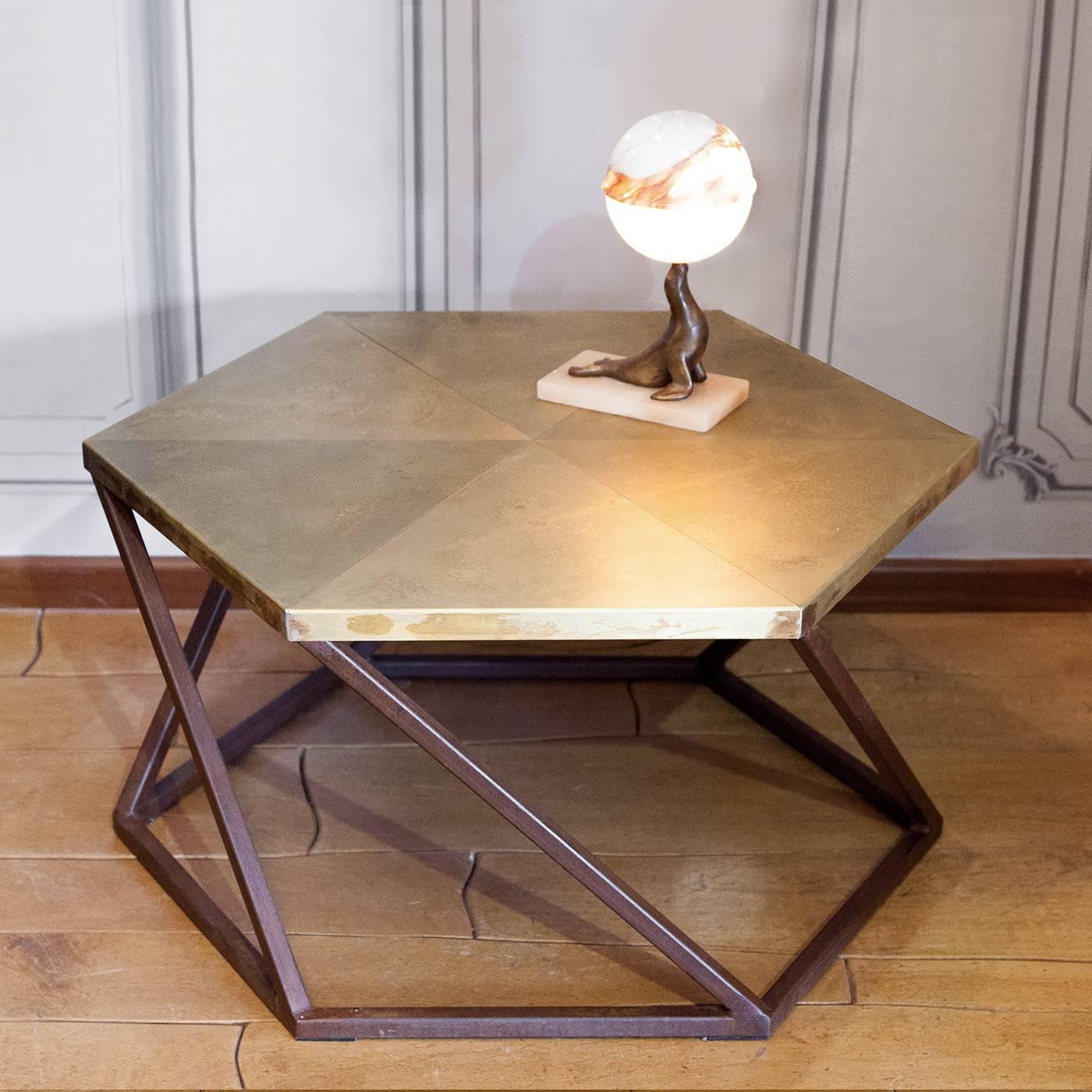 This sophisticated coffee table features a hexagonal base in oxidized iron from which its legs stem diagonally to connect to the corners of the hexagon that directly supports the top. The top is in multi-ply wood with a cover in triangular sheets of