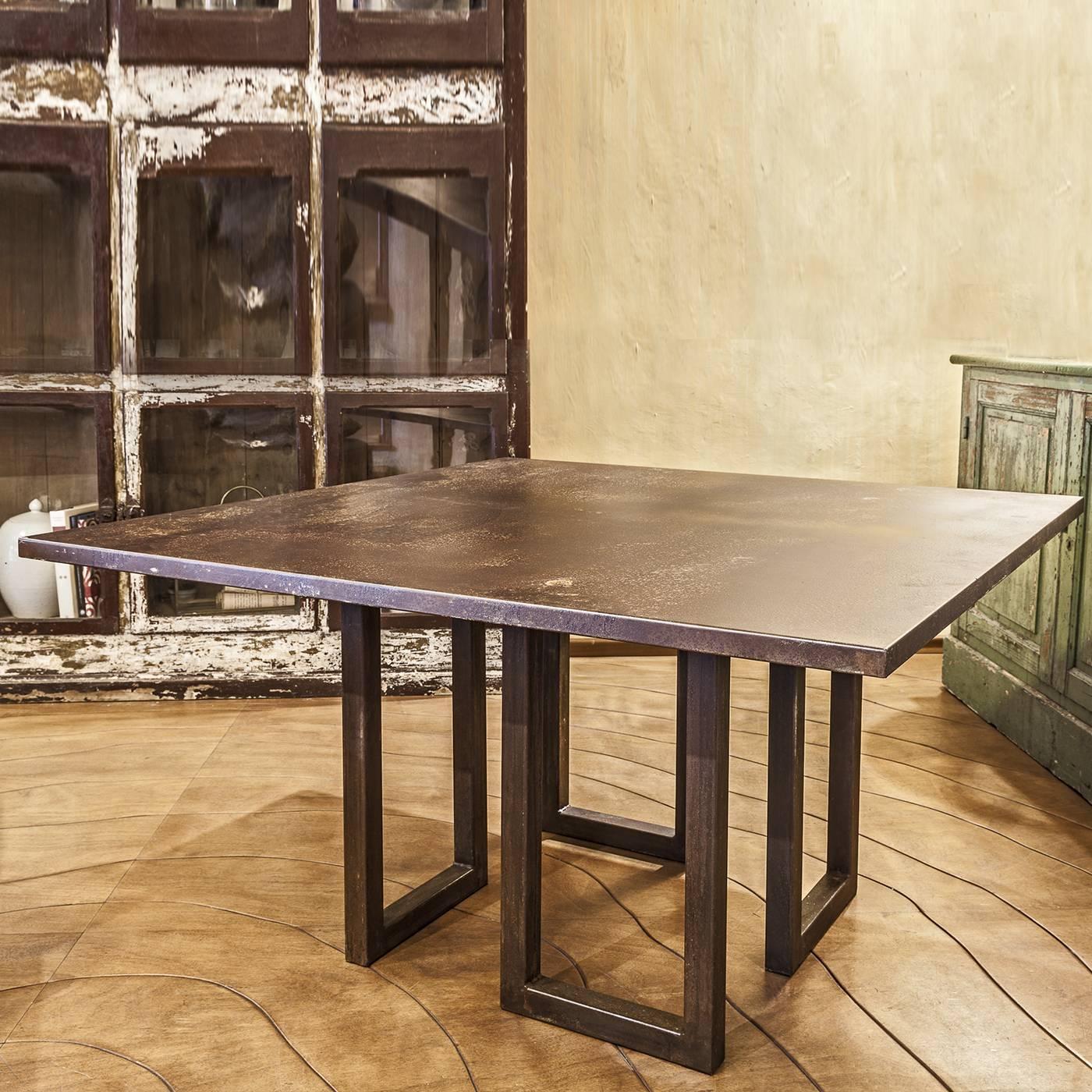 This striking table features a structure made of four rectangles in thick oxidized iron that support a top in multi-ply wood that was given a cover in oxidized iron to match the base, and features also the same thickness. Modern in the choice of