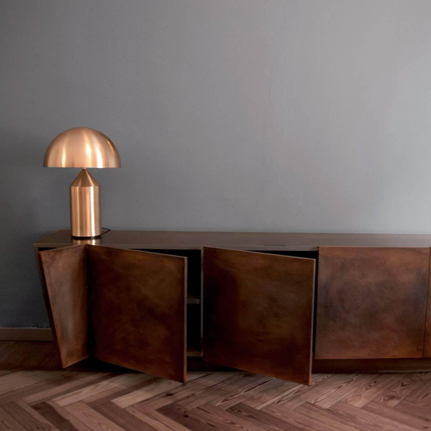 A distinctive rigor of lines, combined with a simple Silhouette and warm colors give this piece a powerful allure. This sideboard is a monolith resting on a plinth base, whose structure is in medium-density fiberboard covered in bronze slabs that